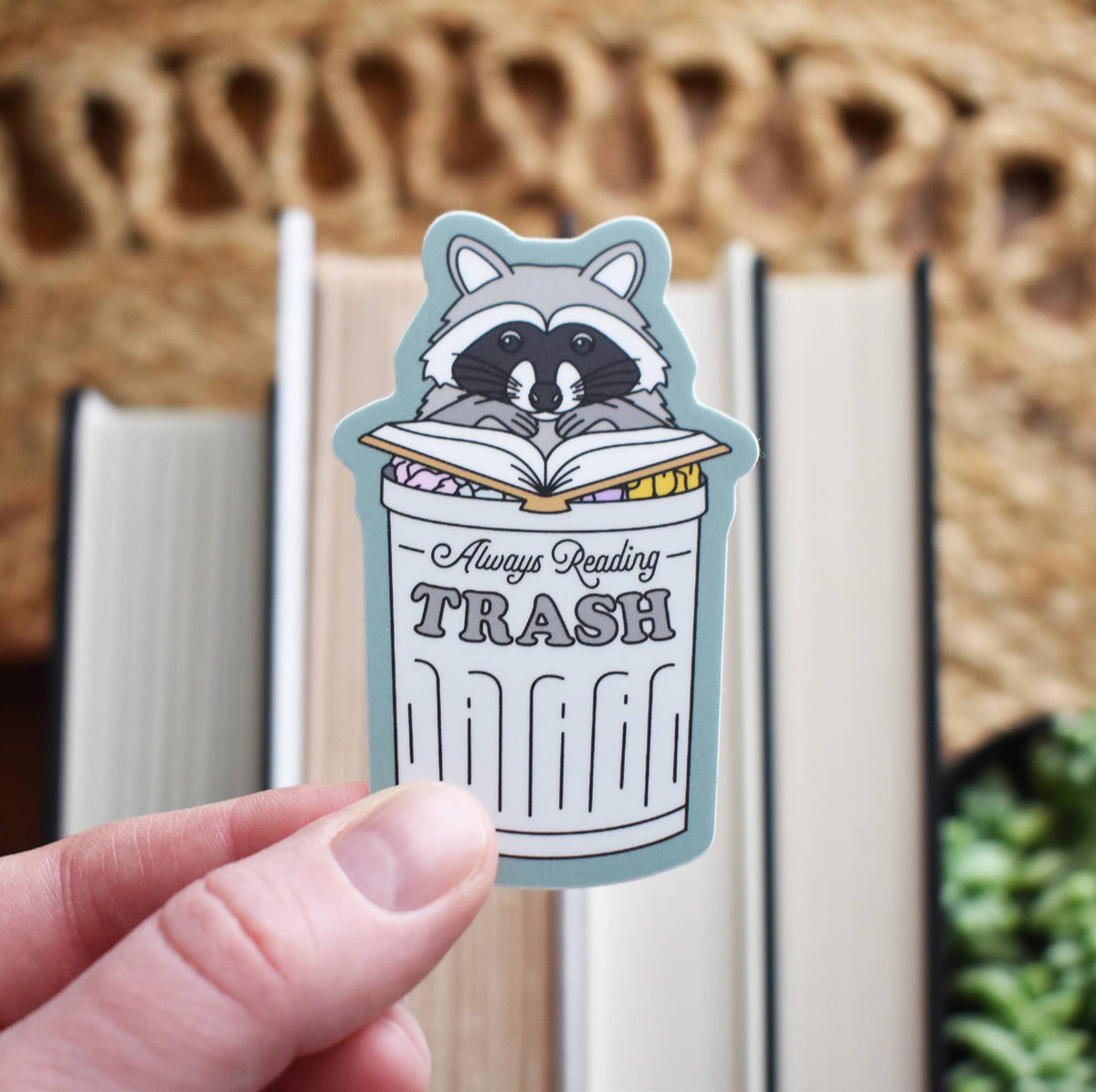 Sticker of a raccoon in a trash can with &