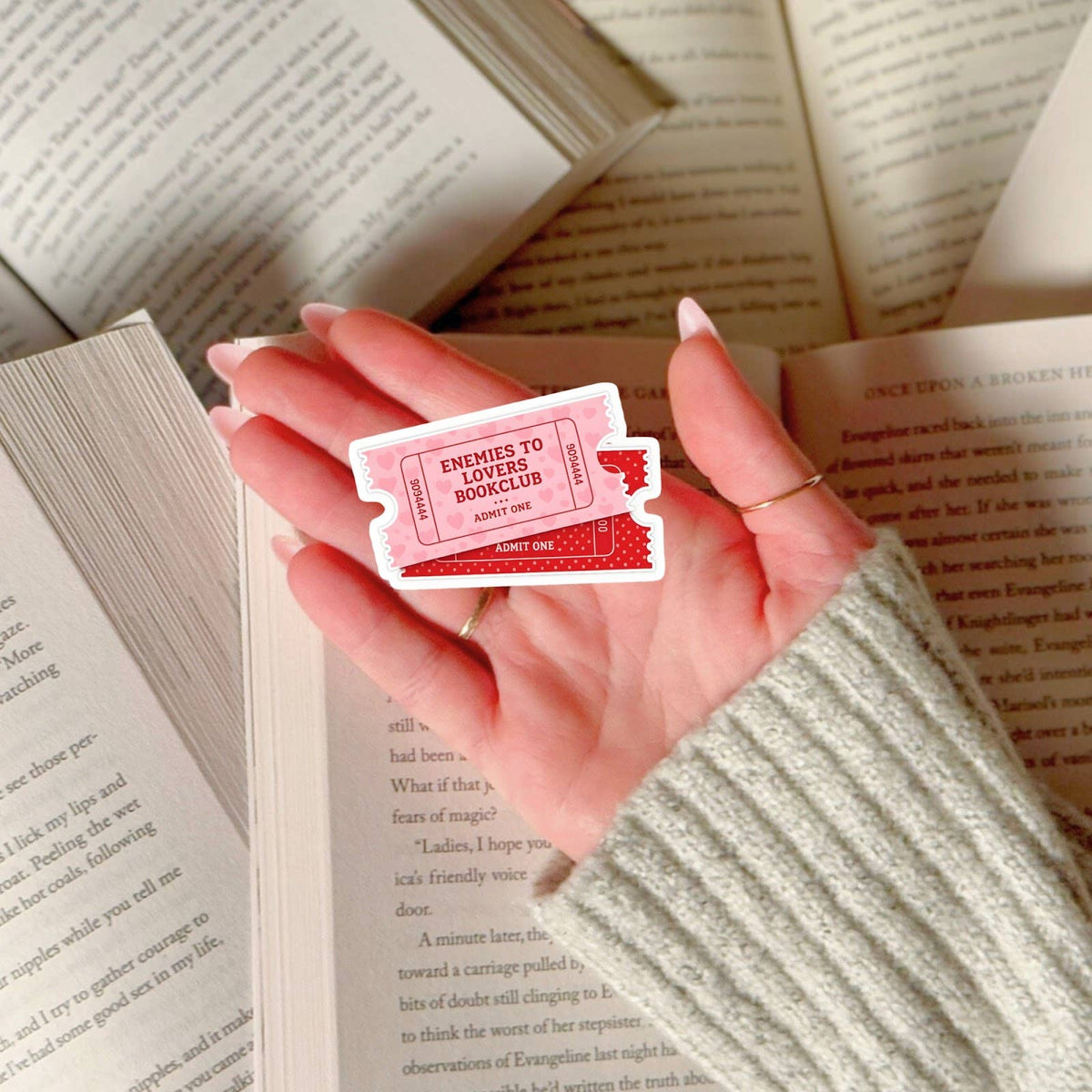 Hand holding a red and white card with text over open books