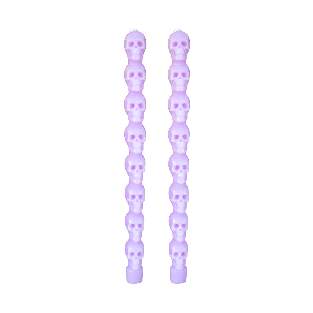 Pair of light purple taper candles molded as stacked skulls, on white.