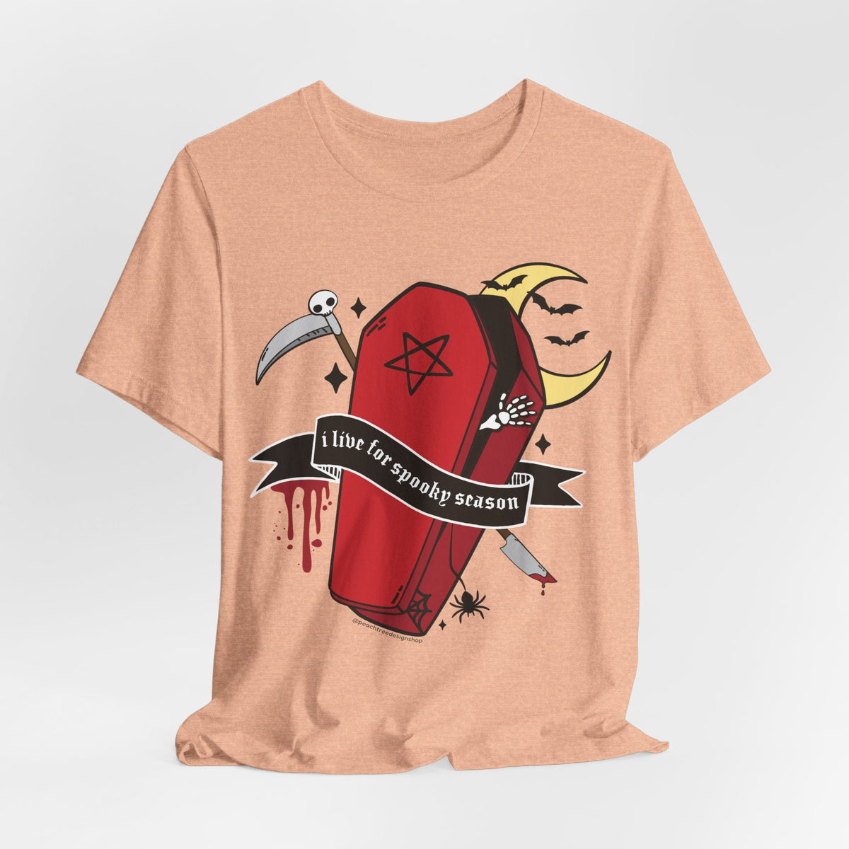 A peach-colored heather t-shirt with a gothic graphic of a red coffin, a scythe, a crescent moon face, and a banner that reads &
