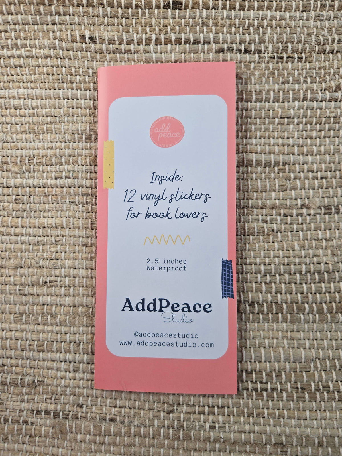 Pink packaging with AddPeace branding on a woven surface