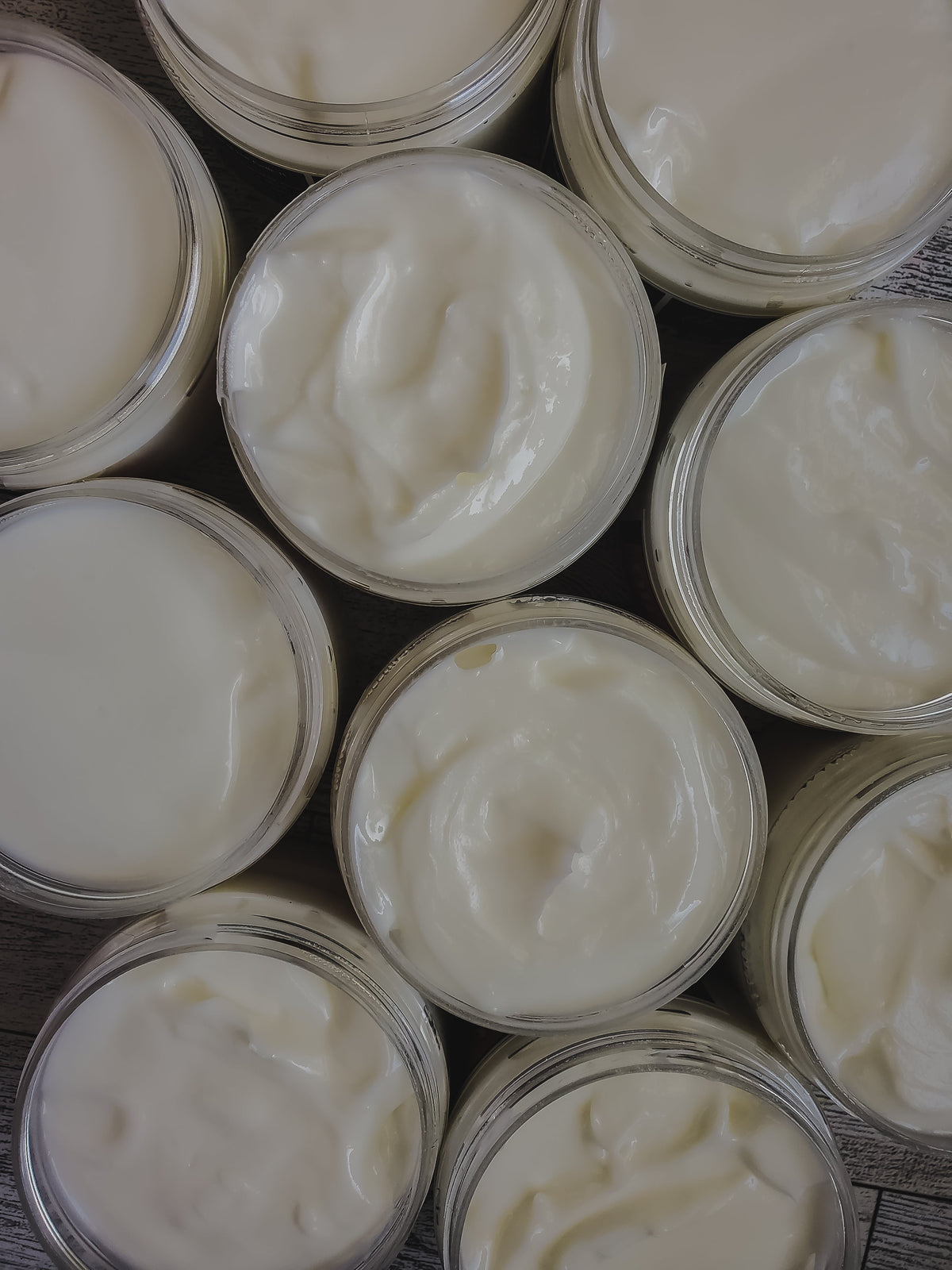 Multiple jars of magnesium lotion with a creamy white substance inside, arranged closely together.