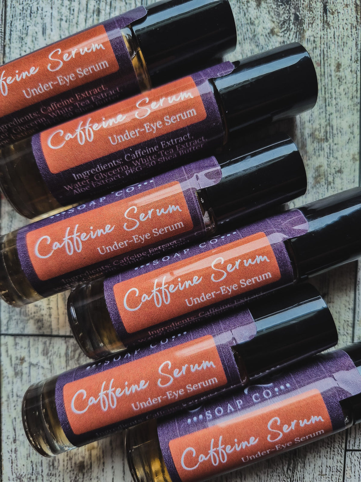 Roll-on bottles of caffeine serum under-eye serum with colorful labels on a dark background