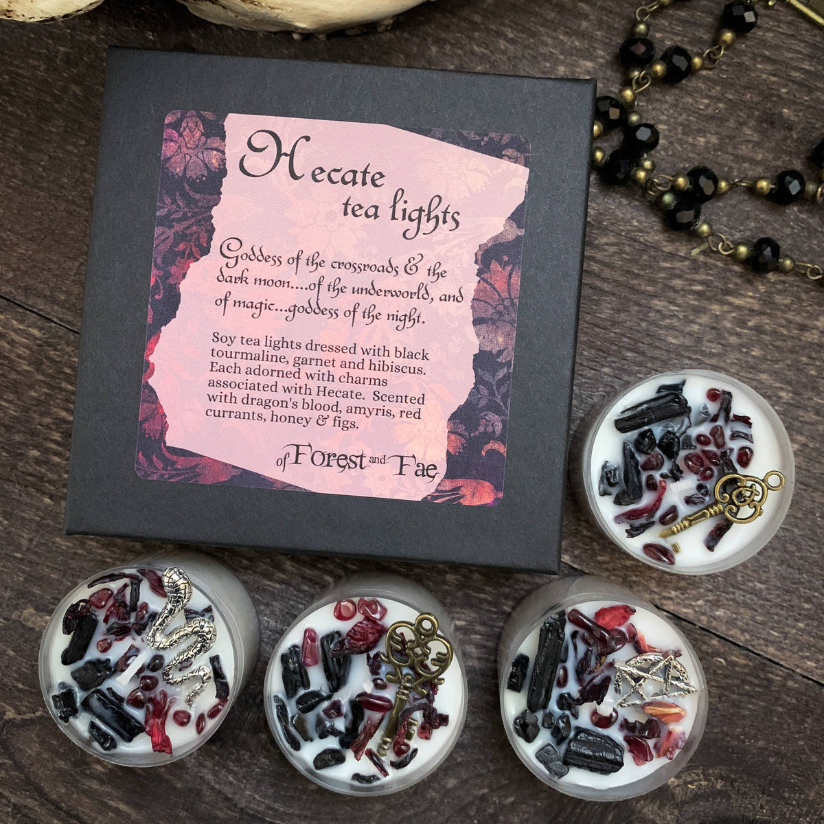 Hecate tea lights packaging with four decorated candles on a wooden surface
