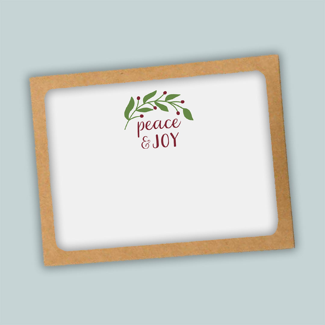 A white card with a brown frame, featuring a decorative wreath and the text "Peace & Joy" in a cursive font.