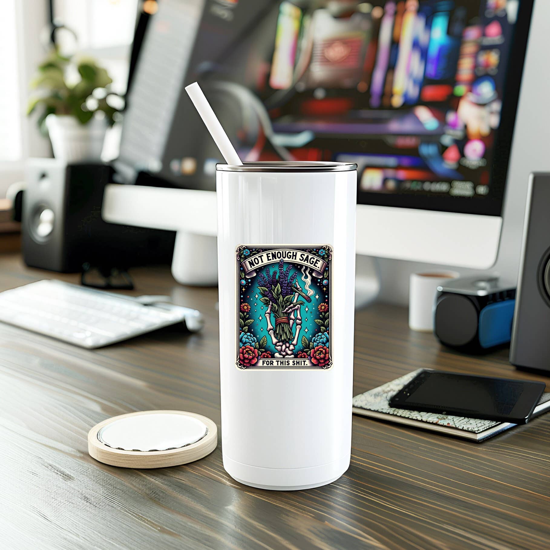 White tumbler with a colorful label on a desk with computer equipment in the background