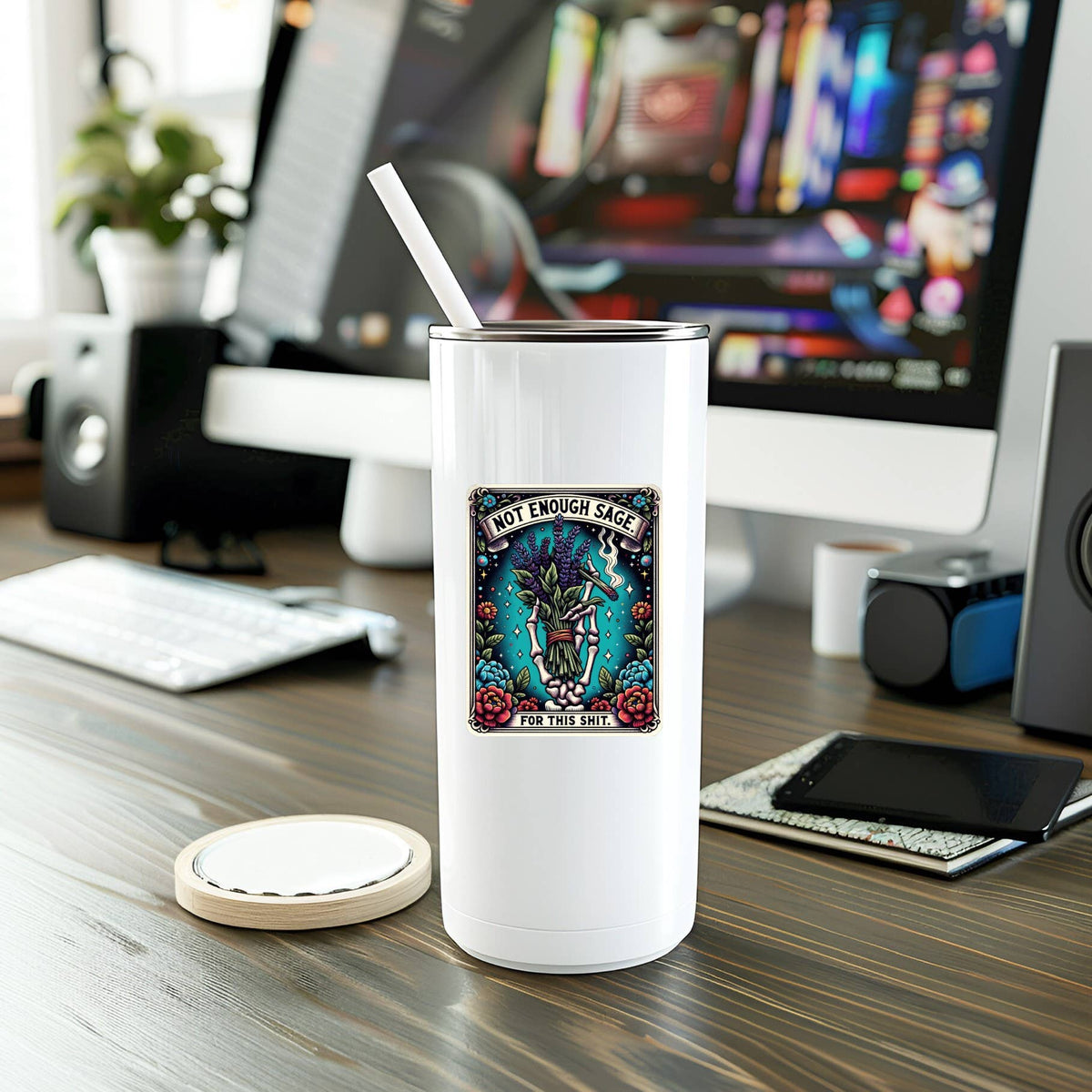 White tumbler with a colorful label on a desk with computer equipment in the background