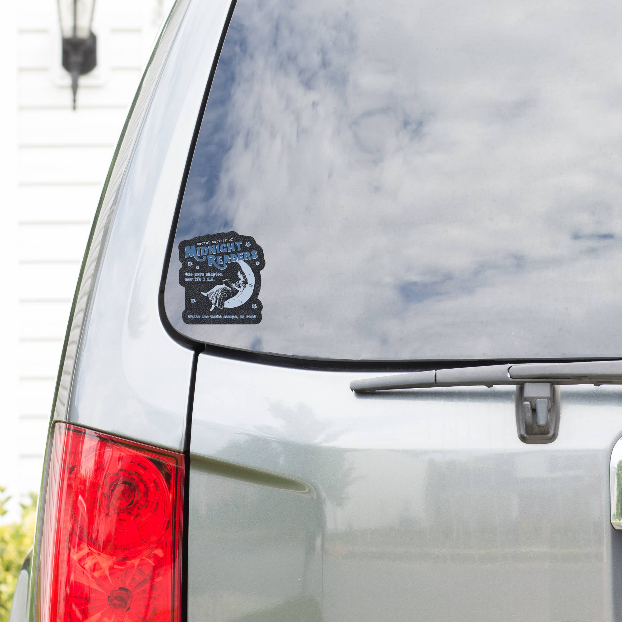 Car with a sticker on the rear window, featuring text and graphics.