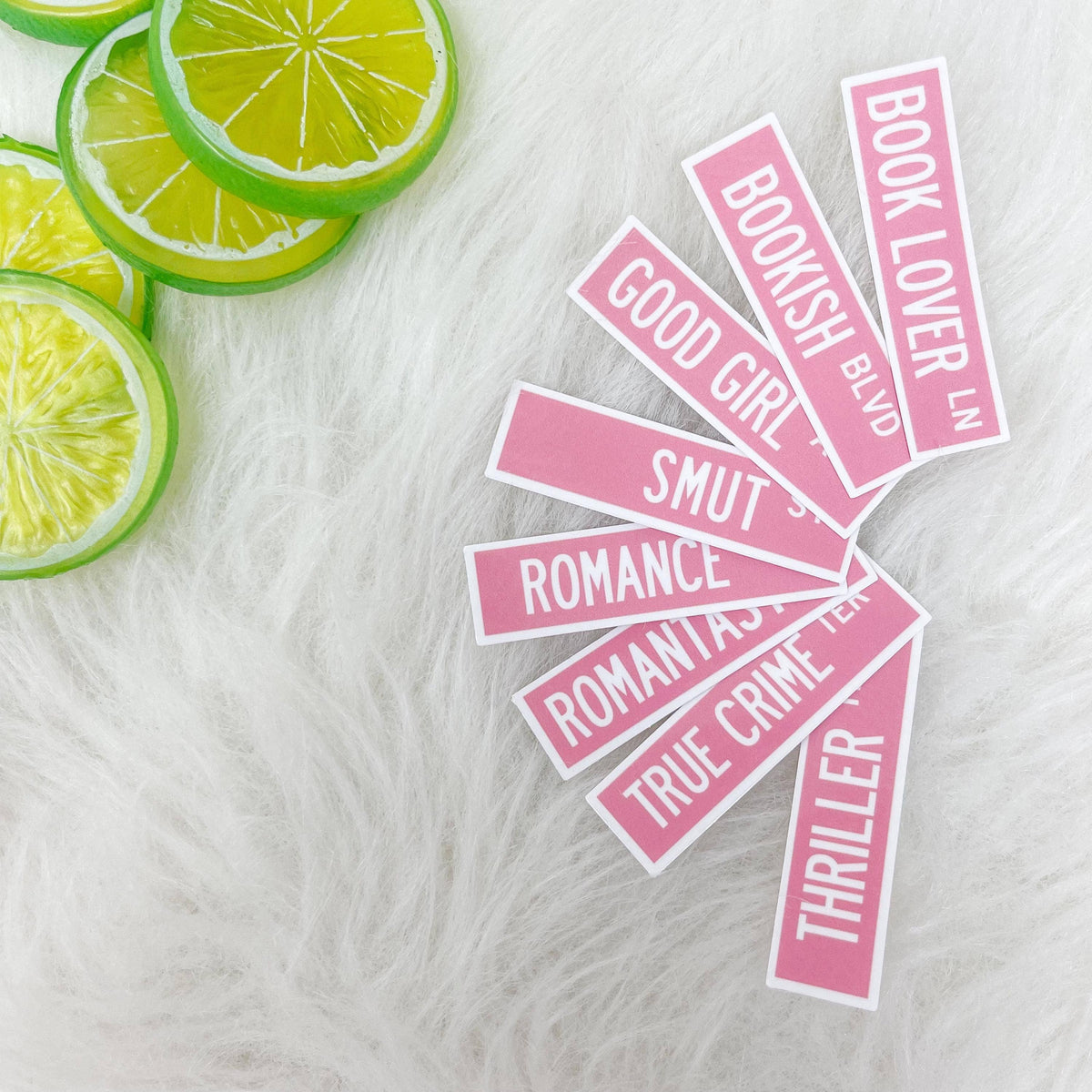Pink book-themed stickers on a white surface with lime slices.