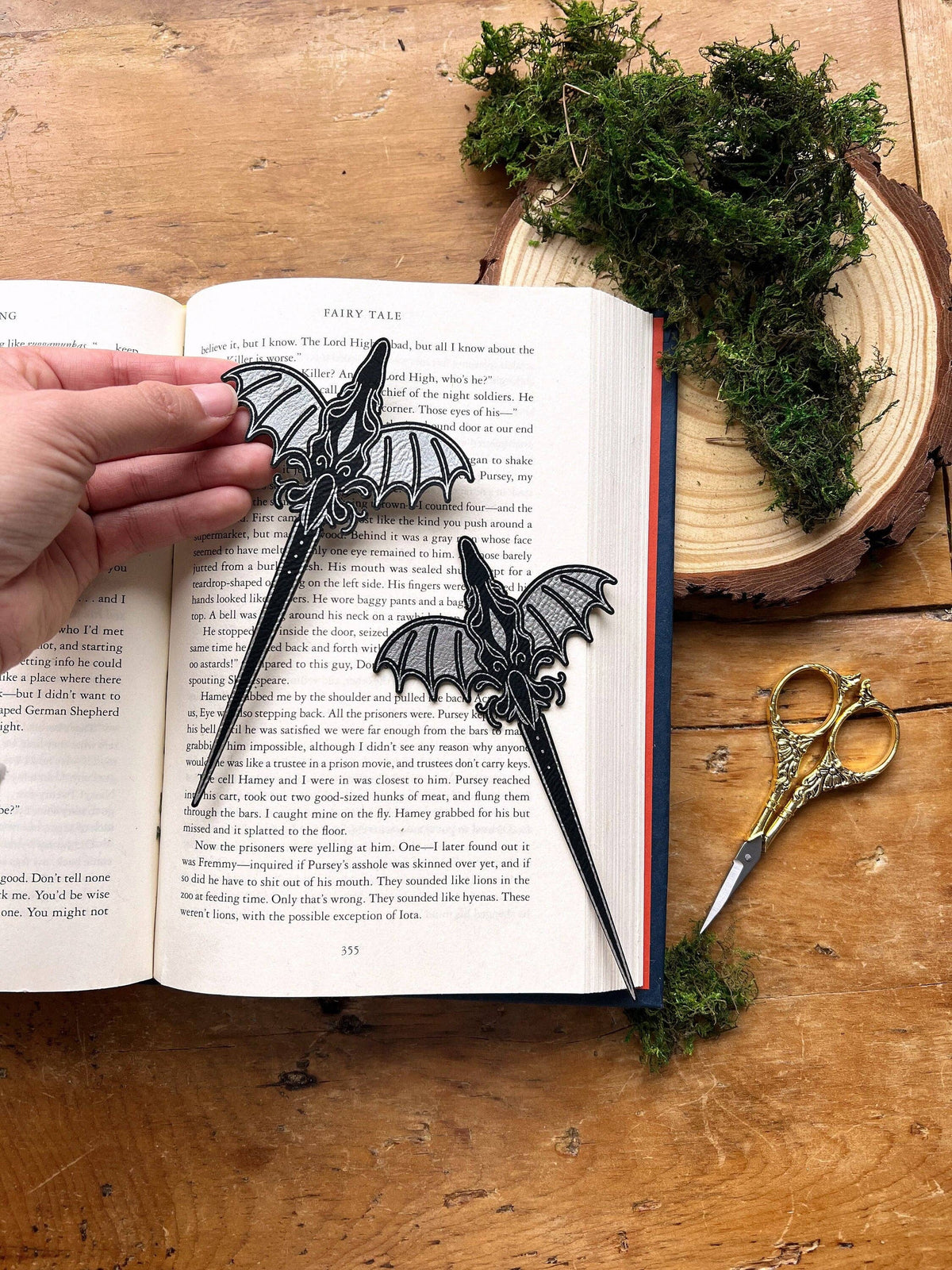Dragon-shaped bookmarks on an open book with a wooden background