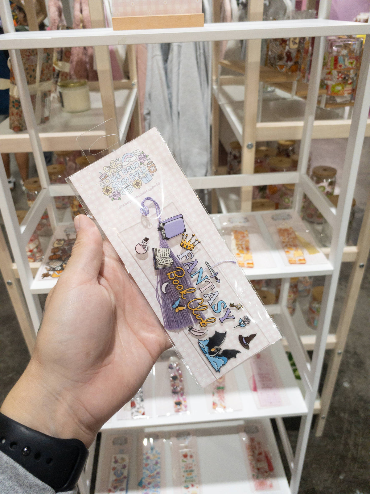Hand holding a card with colorful designs in a store setting