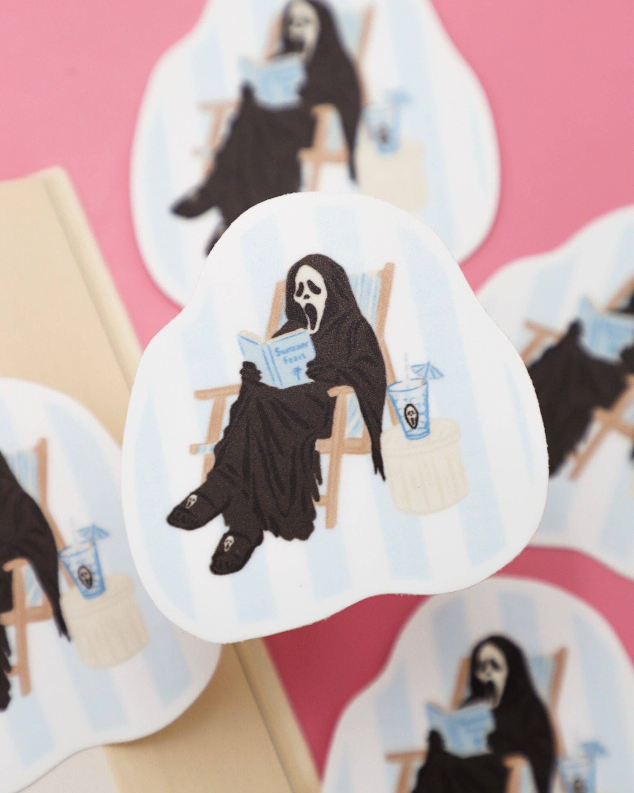 Sticker of a grim reaper reading a book on a pink background