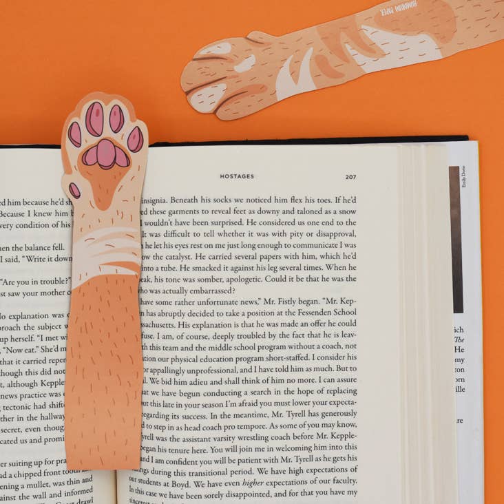 Bookmark with paw design on an open book against an orange background