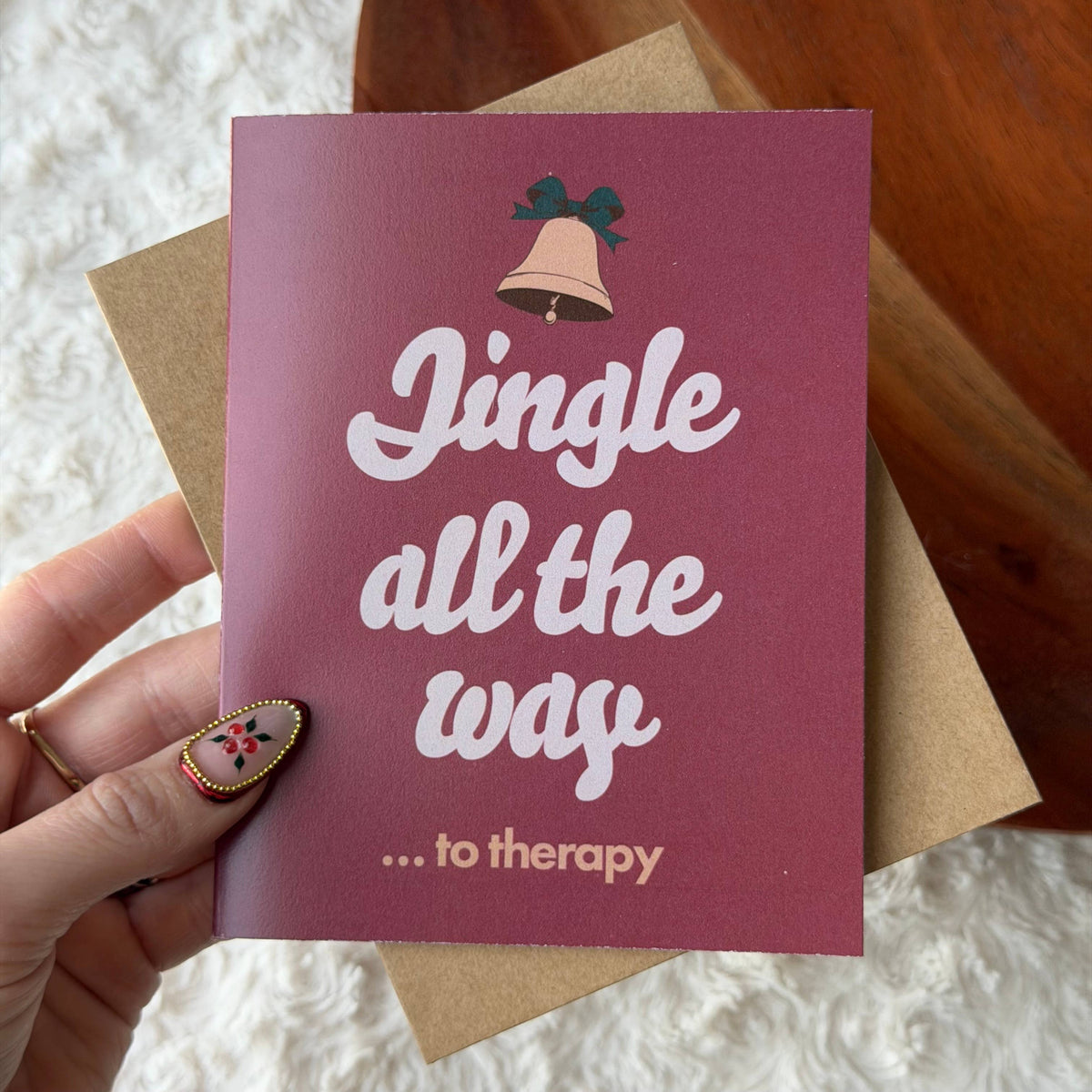A hand holds a maroon greeting card that reads &