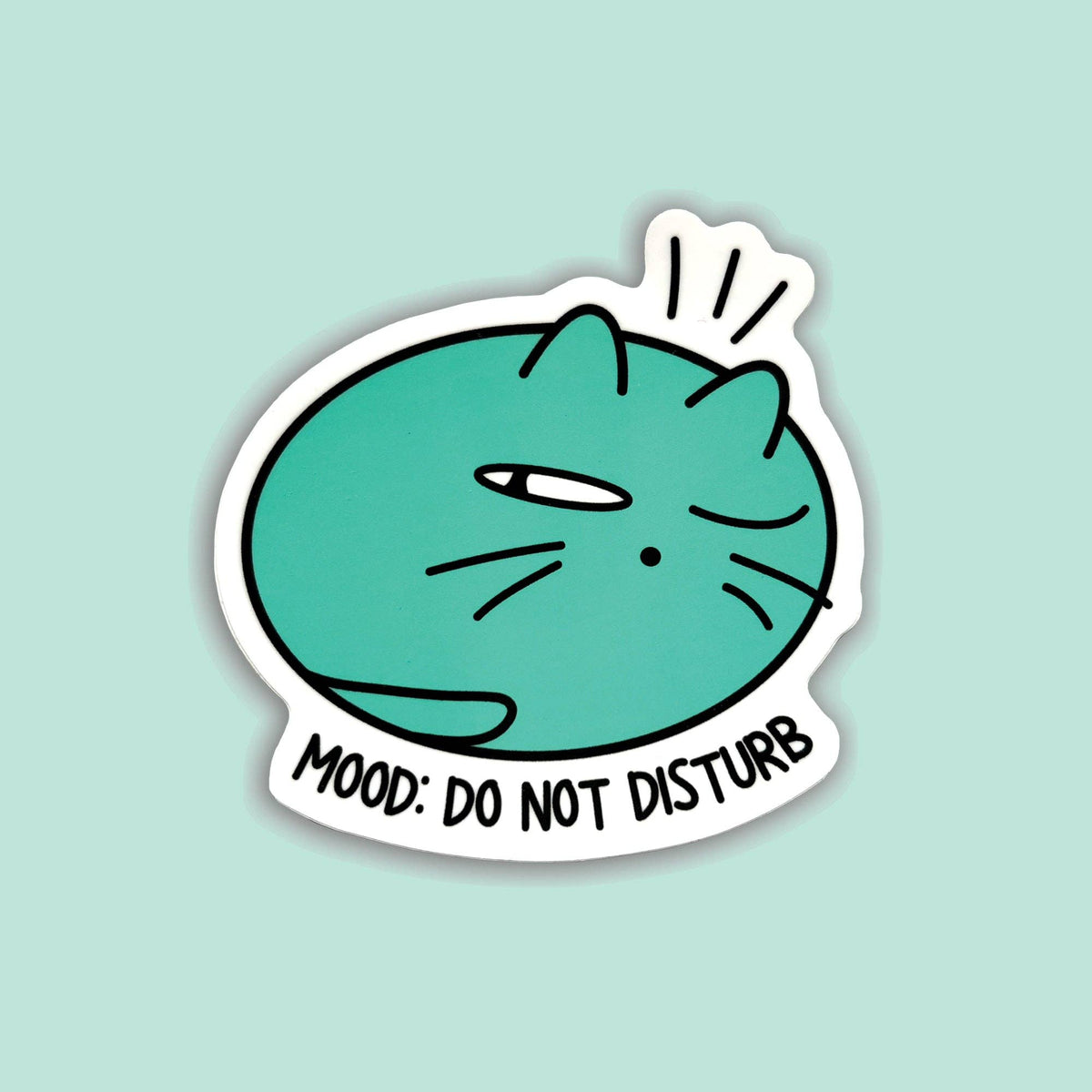 A die-cut sticker featuring a teal cartoon cat with one eye closed and the text &