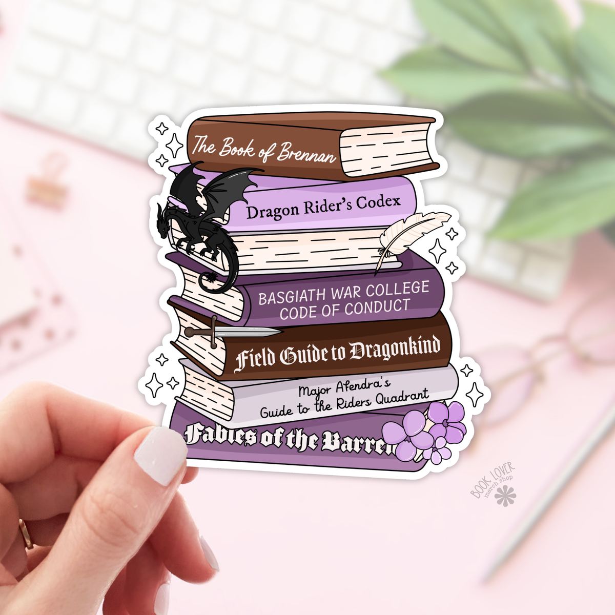 Sticker of stacked books with titles held by a hand on a blurred background