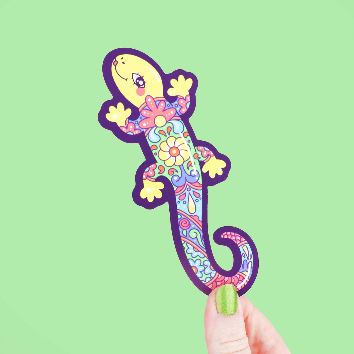 Colorful lizard-shaped bookmark held against a green background