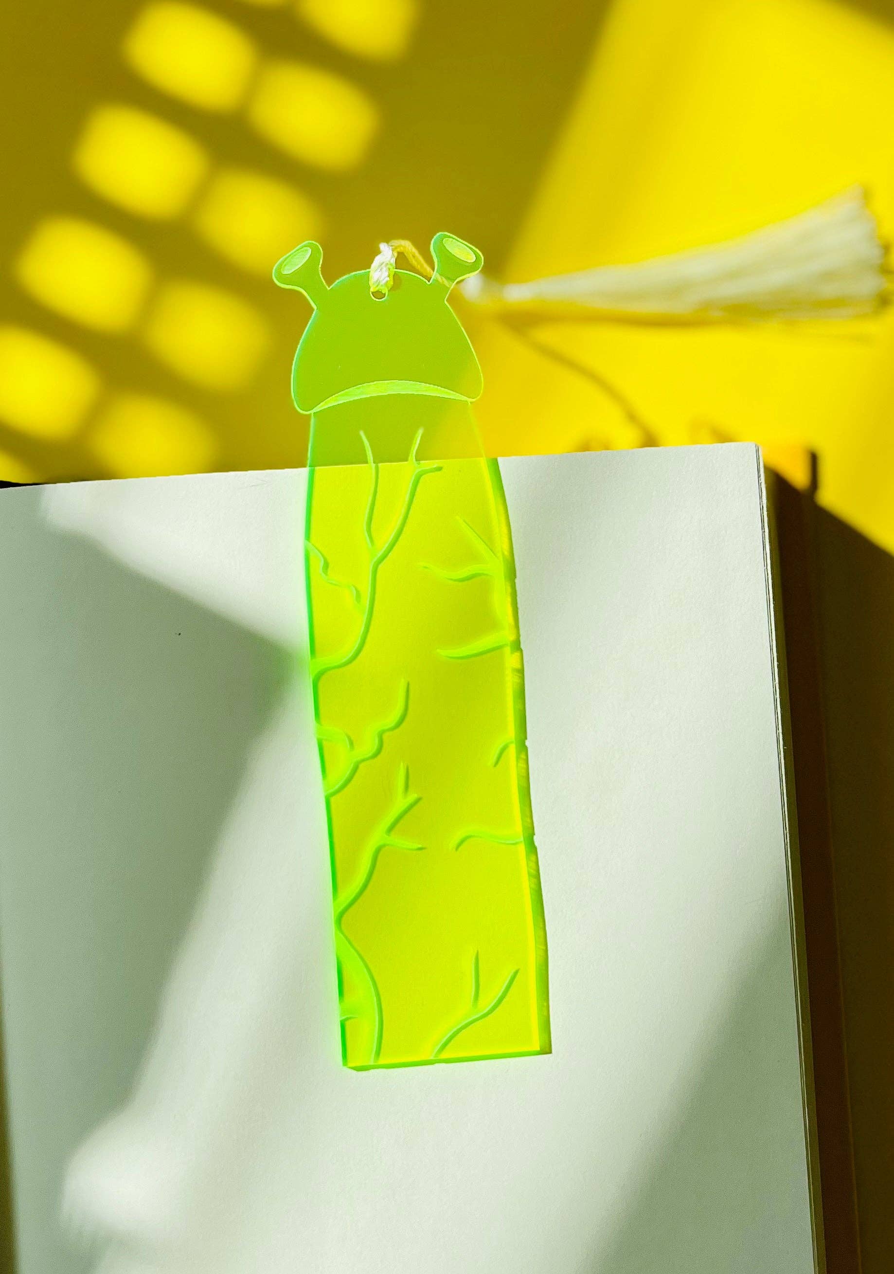 Green ogre-shaped bookmark on a white surface with yellow background