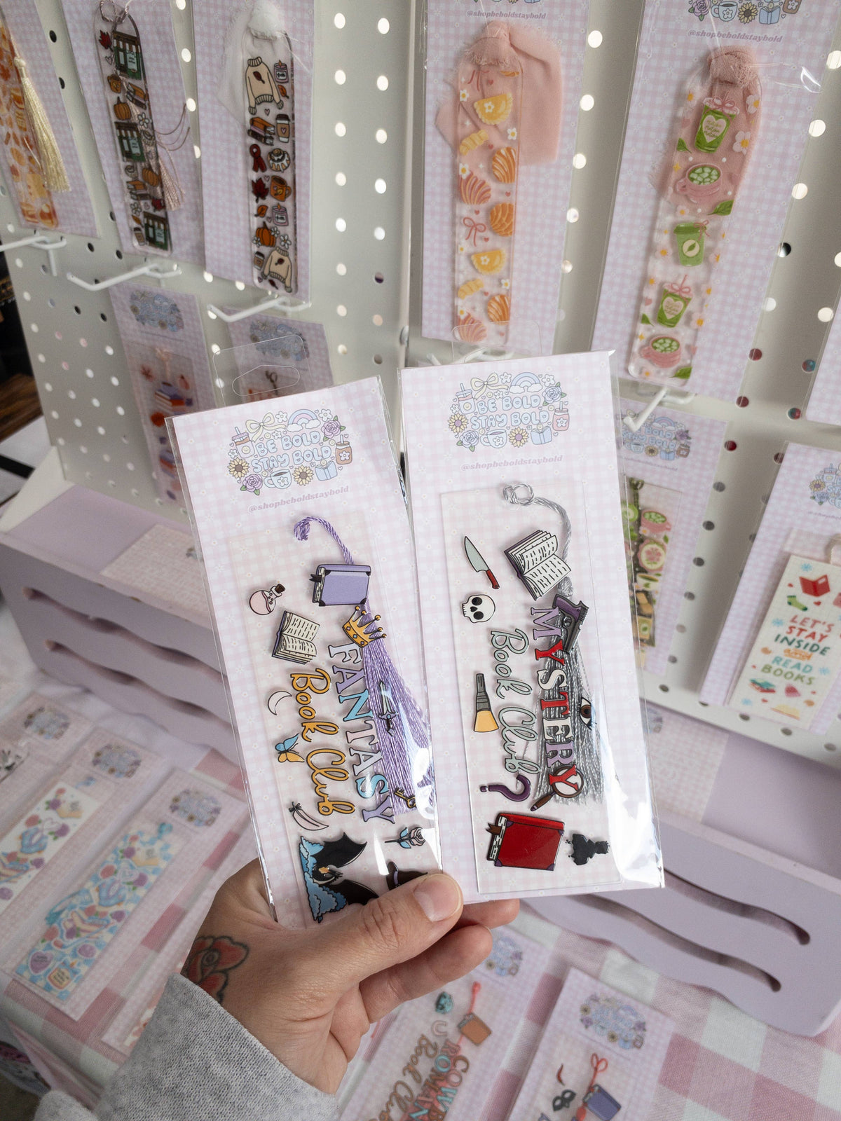 Hand holding a set of decorative bookmarks with various designs on a display background.