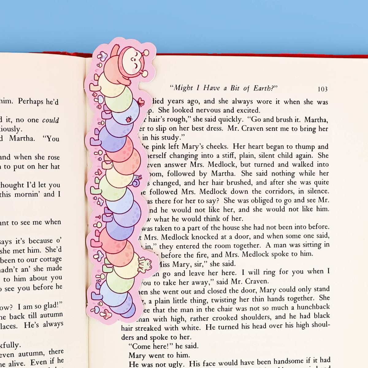 Colorful caterpillar-shaped bookmark on an open book with a blue background