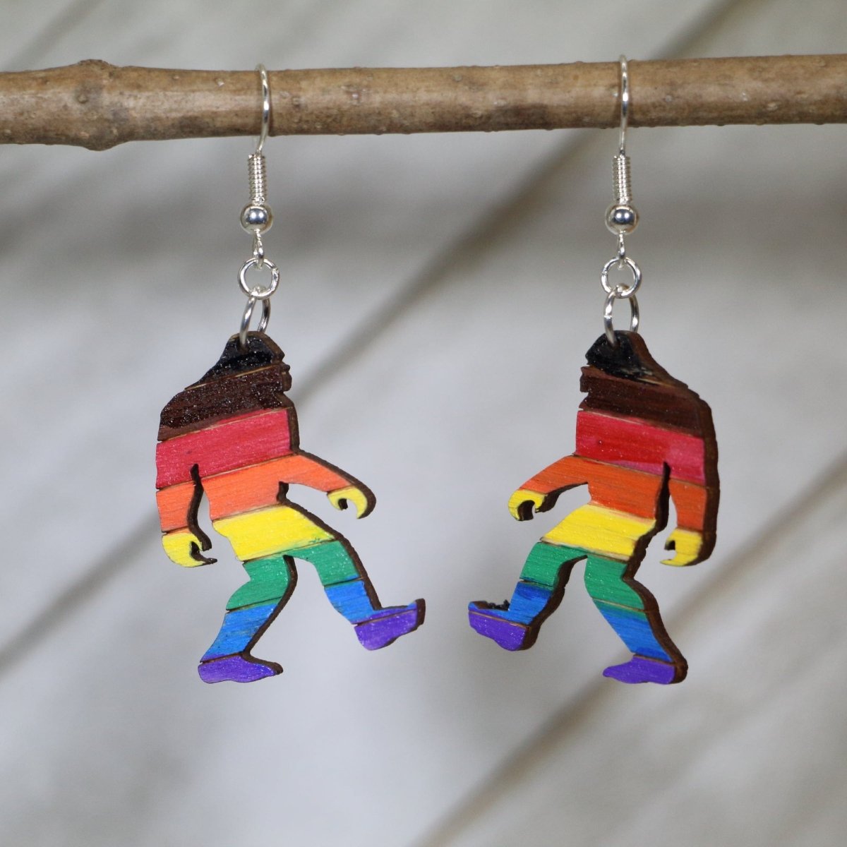 Hand-painted wooden Bigfoot rainbow pride dangle earrings with colorful Sasquatch design and hypoallergenic sterling silver hooks, lightweight LGBTQ statement jewelry earrings for cryptid lovers and pride style