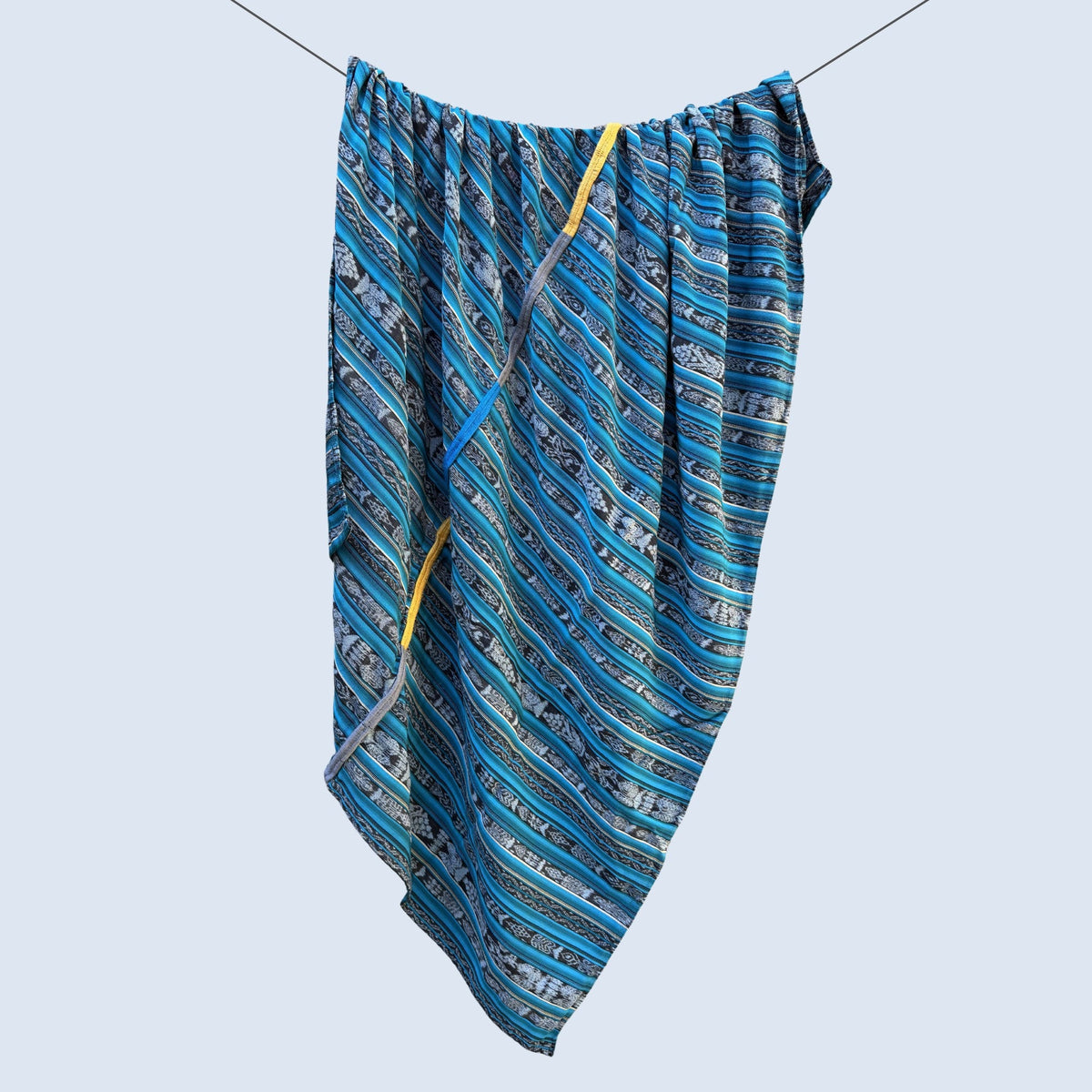 Blue patterned fabric hanging on a clothesline against a light blue background