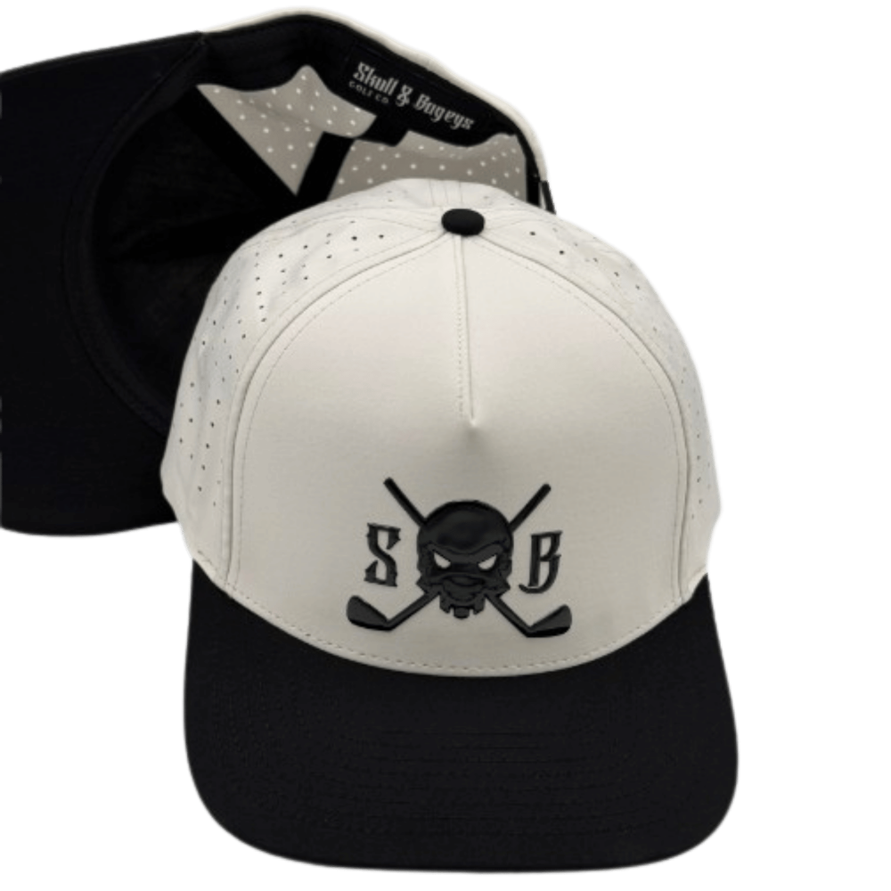 A structured baseball cap shown from the front and back. The front panel is off-white with a black embroidered skull and crossed golf clubs logo flanked by the letters &
