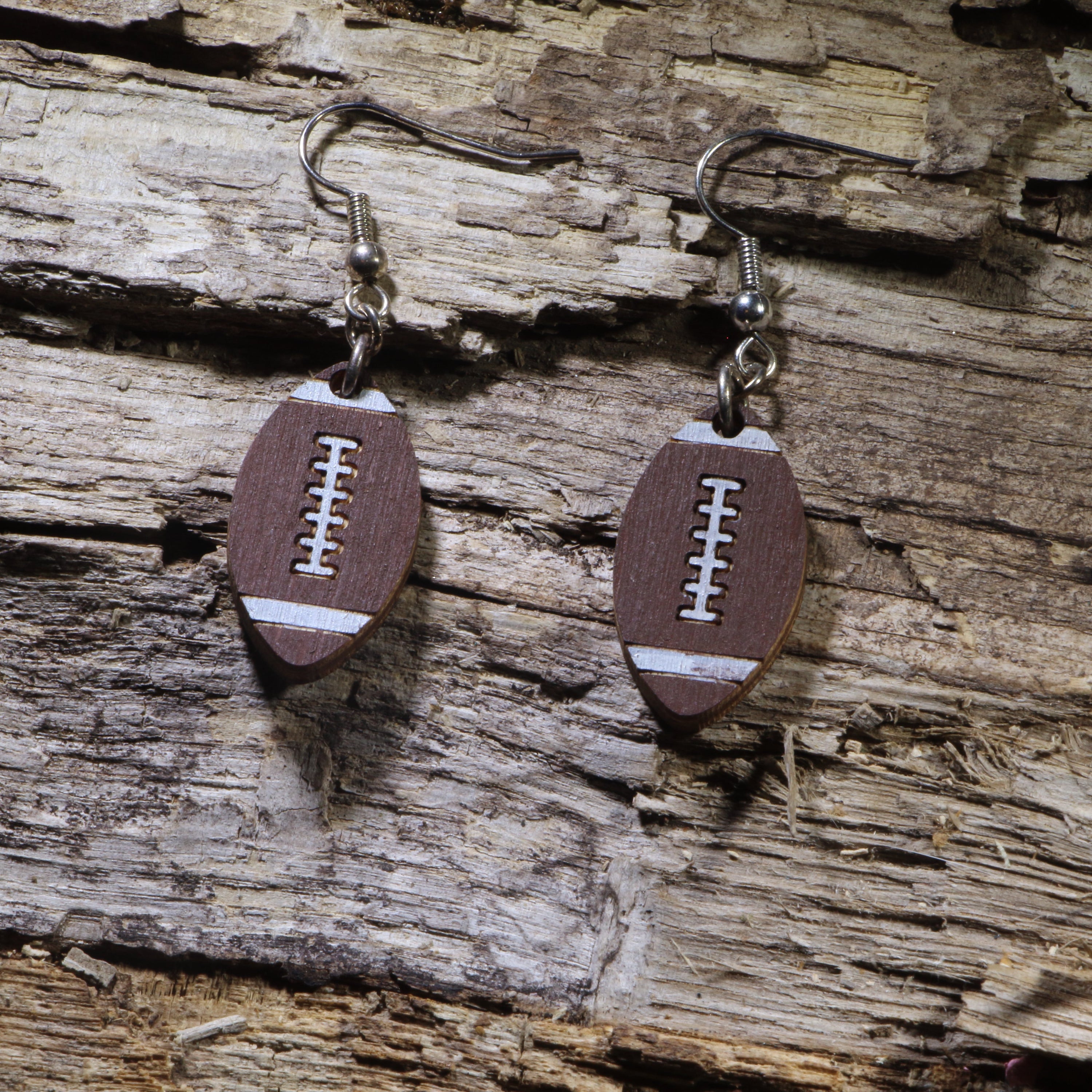 Hand-painted wooden football dangle earrings featuring a classic brown football with white stripes and detailed laces. Lightweight sports earrings with hypoallergenic .925 sterling silver hooks, perfect for football fans, players, coaches, team moms, tailgates, game days, and celebrating every touchdown.