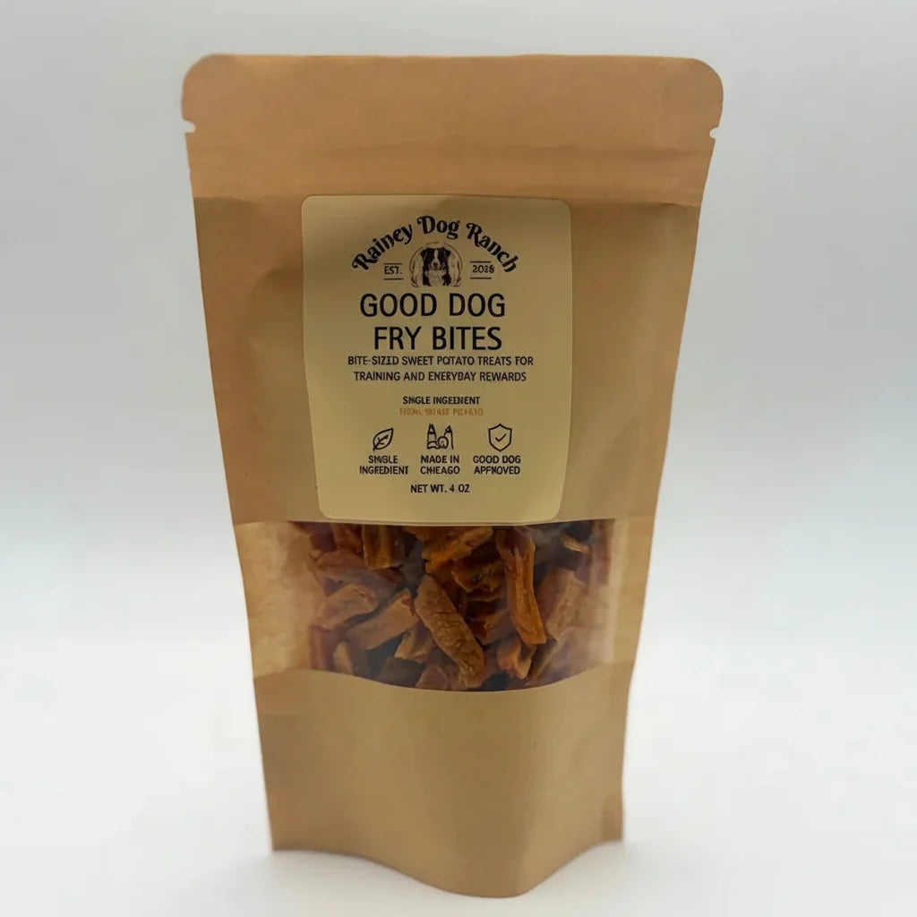 A stand-up kraft paper pouch of Rainey Dog Ranch Good Dog Fry Bites, featuring a clear window showing the brown fried dog treats inside, set against a plain white background.