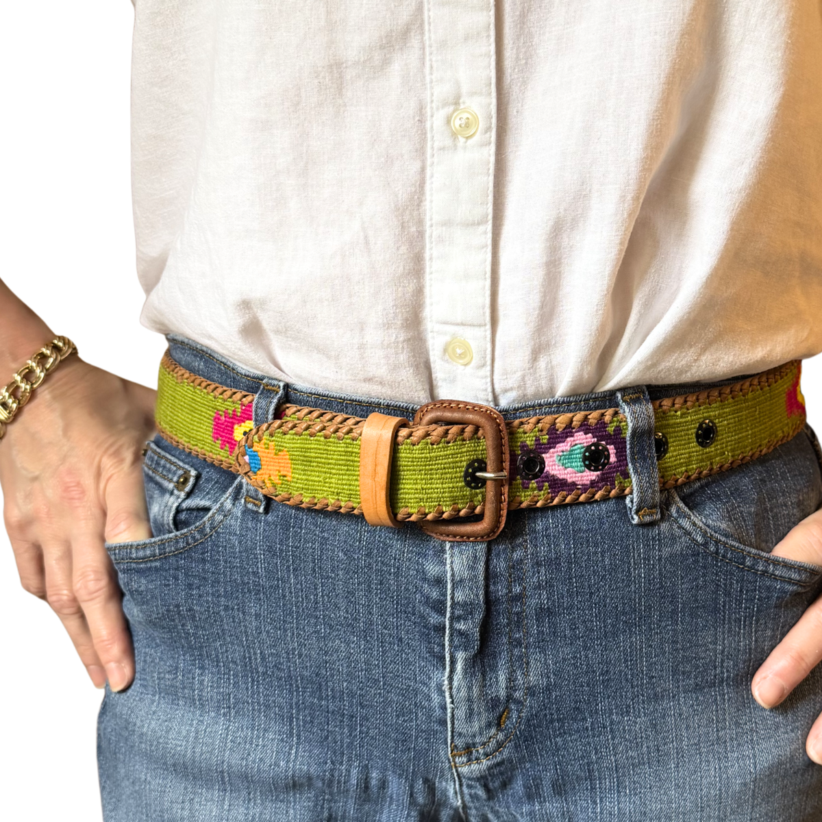 Person wearing a colorful belt with a white shirt and blue jeans.