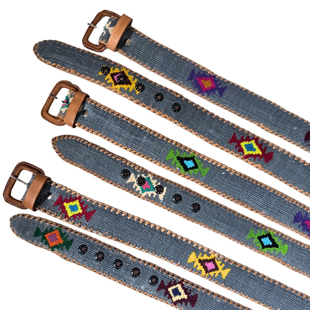 Five denim-style belts with brown leather buckles and trim, decorated with colorful geometric beadwork, arranged diagonally on a white background.