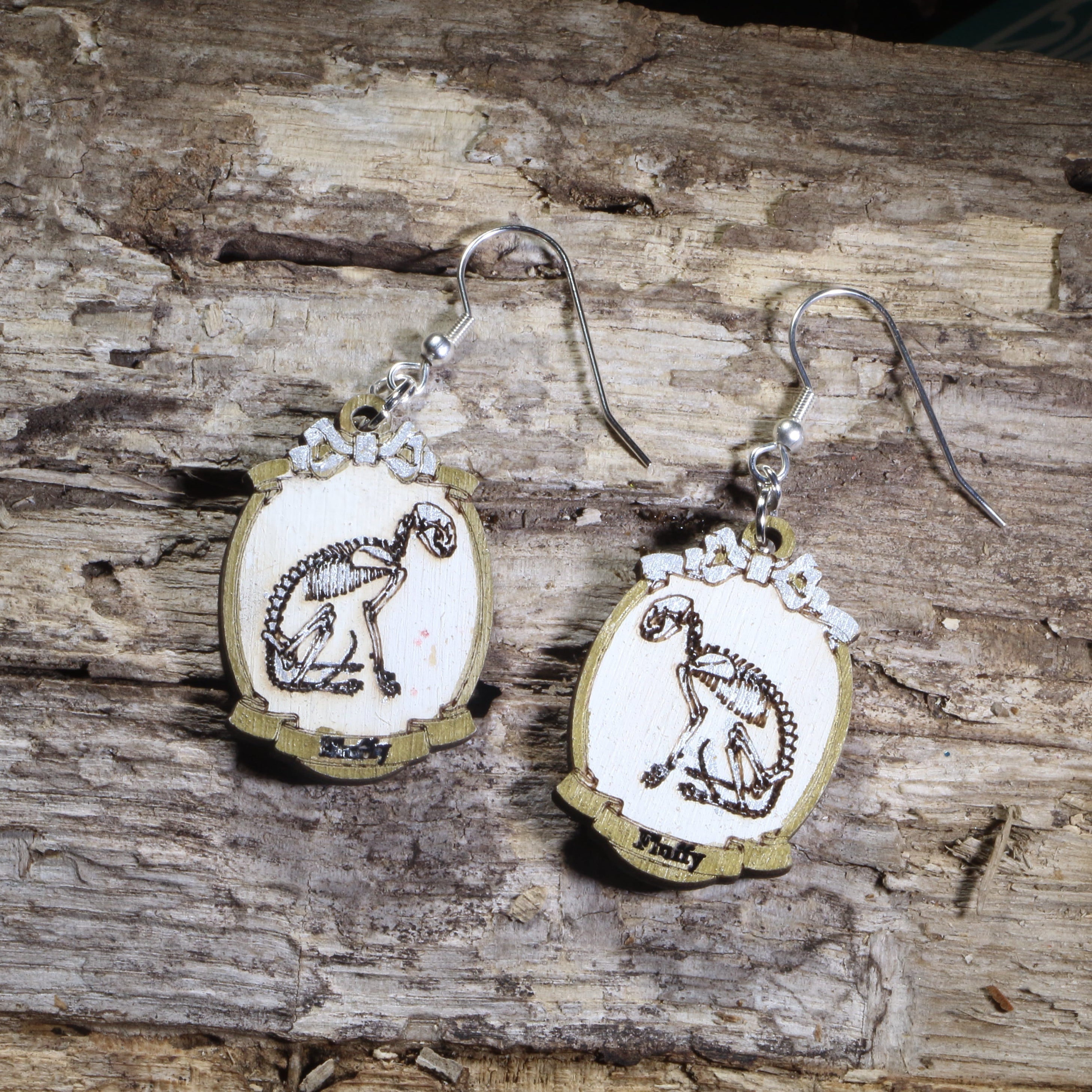 Hand-painted wooden cat skeleton cameo dangle earrings featuring an elegant feline skeleton framed in an ornate vintage cameo on hypoallergenic .925 sterling silver hooks. Lightweight gothic jewelry for cat lovers, Halloween enthusiasts, dark academia fans, veterinarians, anatomy enthusiasts, and collectors of spooky accessories.