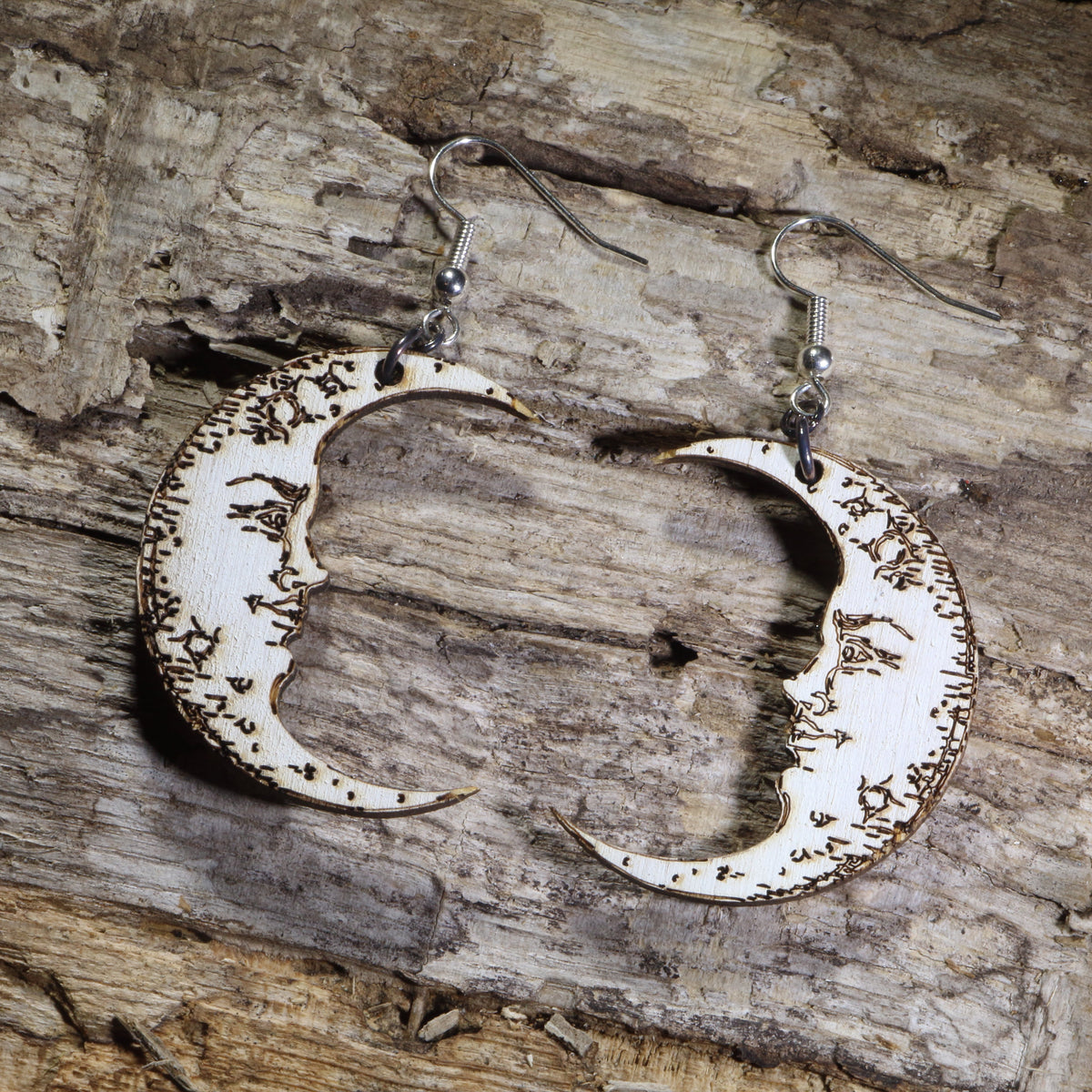 Hand-painted wooden crescent moon dangle earrings featuring engraved vintage moon face details on hypoallergenic .925 sterling silver hooks. Lightweight celestial jewelry perfect for moon lovers, astrology enthusiasts, witchy style, gothic fashion, and lunar-inspired accessories.