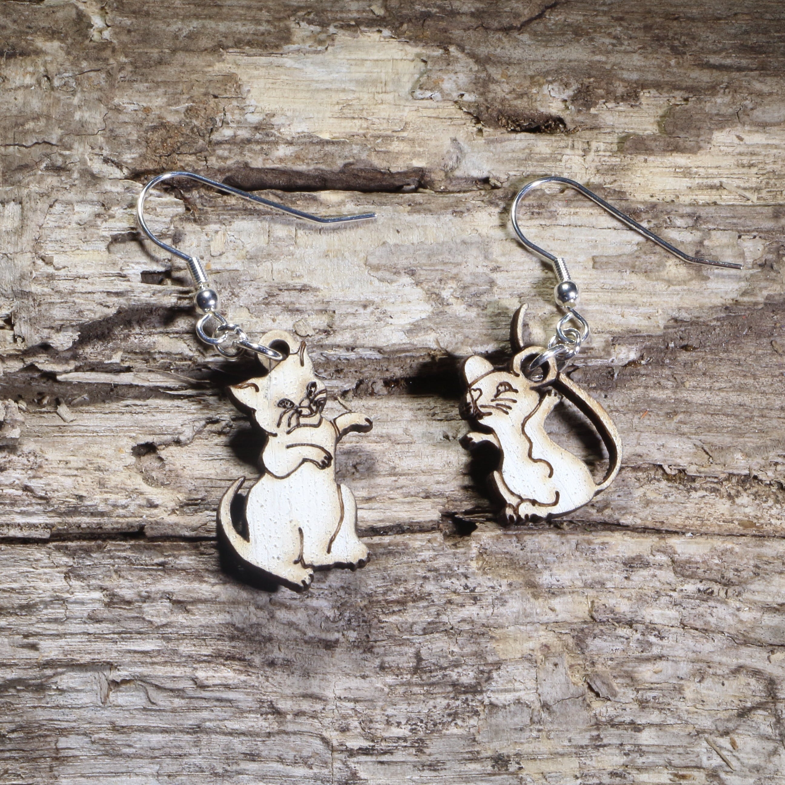 Hand-painted wooden mismatched cat and mouse dangle earrings featuring a playful white cat reaching toward a smiling mouse on hypoallergenic .925 sterling silver hooks. Lightweight animal jewelry for cat lovers, mouse enthusiasts, pet owners, and anyone who enjoys whimsical, playful accessories.