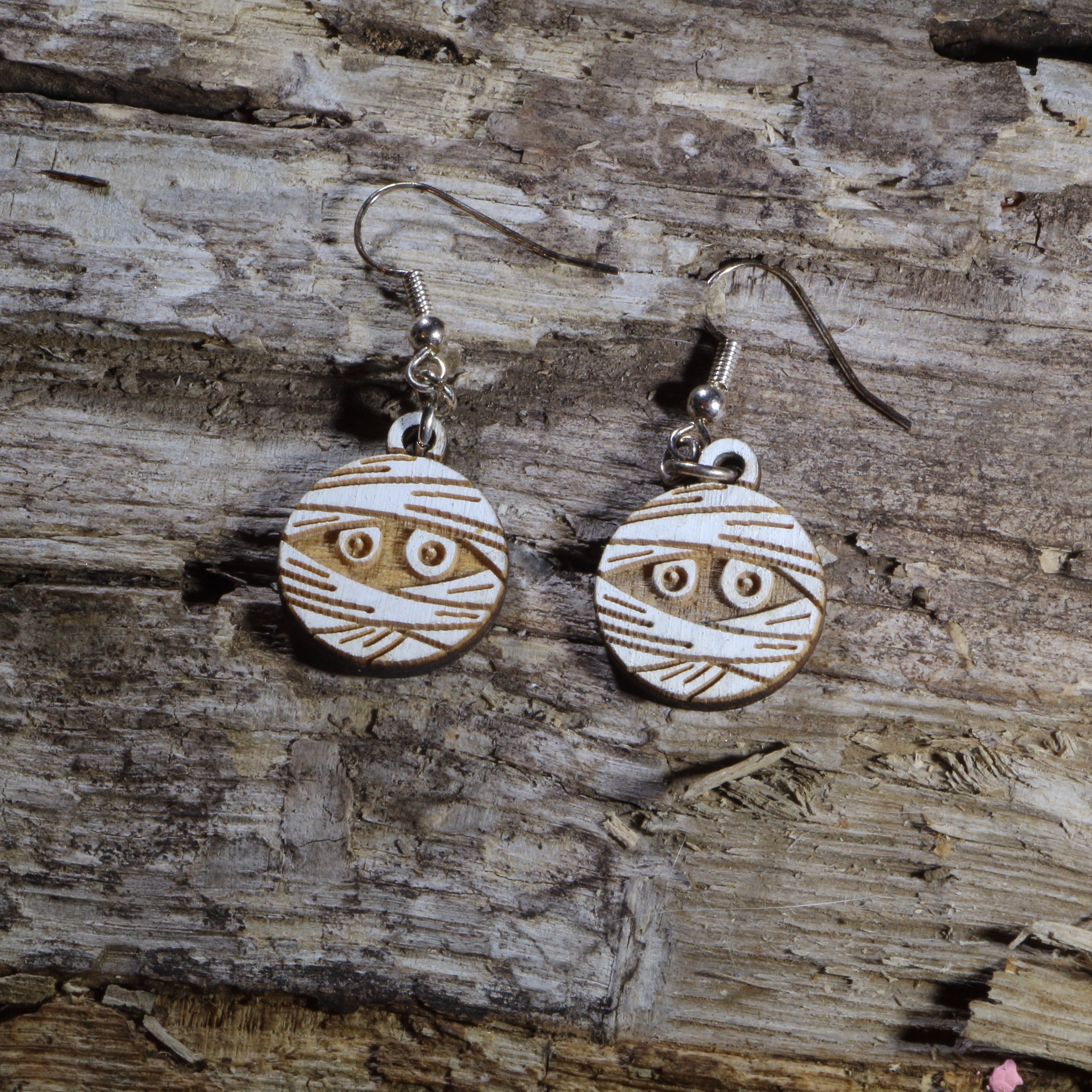 Hand-painted wooden mummy dangle earrings featuring a wrapped Halloween mummy with spooky details. Lightweight Halloween earrings with hypoallergenic .925 sterling silver hooks, perfect for spooky season, trick-or-treat events, Halloween parties, haunted attractions, and anyone who loves creepy-cute Halloween jewelry.