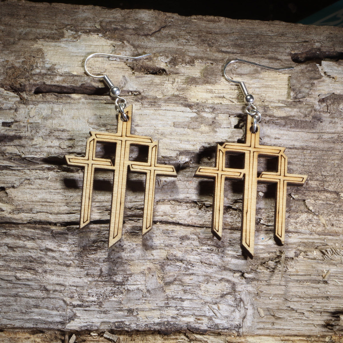 Hand-painted wooden triple cross dangle earrings featuring three Christian crosses symbolizing the crucifixion of Jesus on hypoallergenic .925 sterling silver hooks. Lightweight Christian faith jewelry for church services, Easter, pastors, Bible study groups, and believers who want to express their faith.