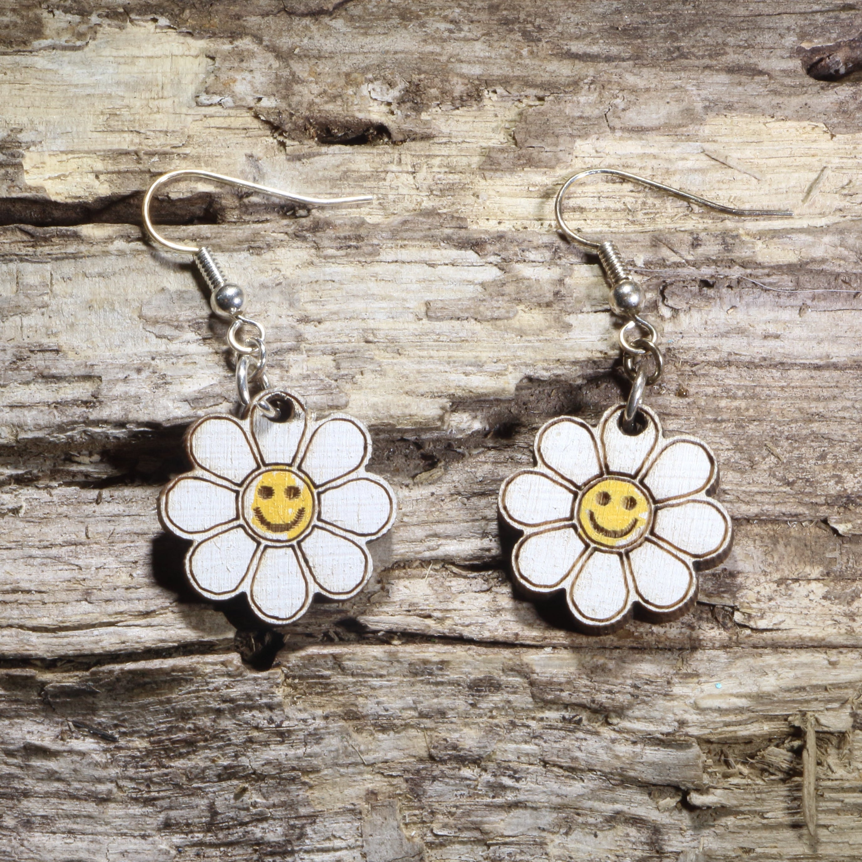 Handcrafted Smiley Daisy wooden dangle earrings featuring cheerful smiling daisy flowers with bright, playful details. Lightweight laser-cut wooden earrings with hypoallergenic .925 sterling silver hooks, perfect for flower lovers, retro 70s fashion, happy aesthetic, spring accessories, cottagecore style, and fun everyday jewelry.