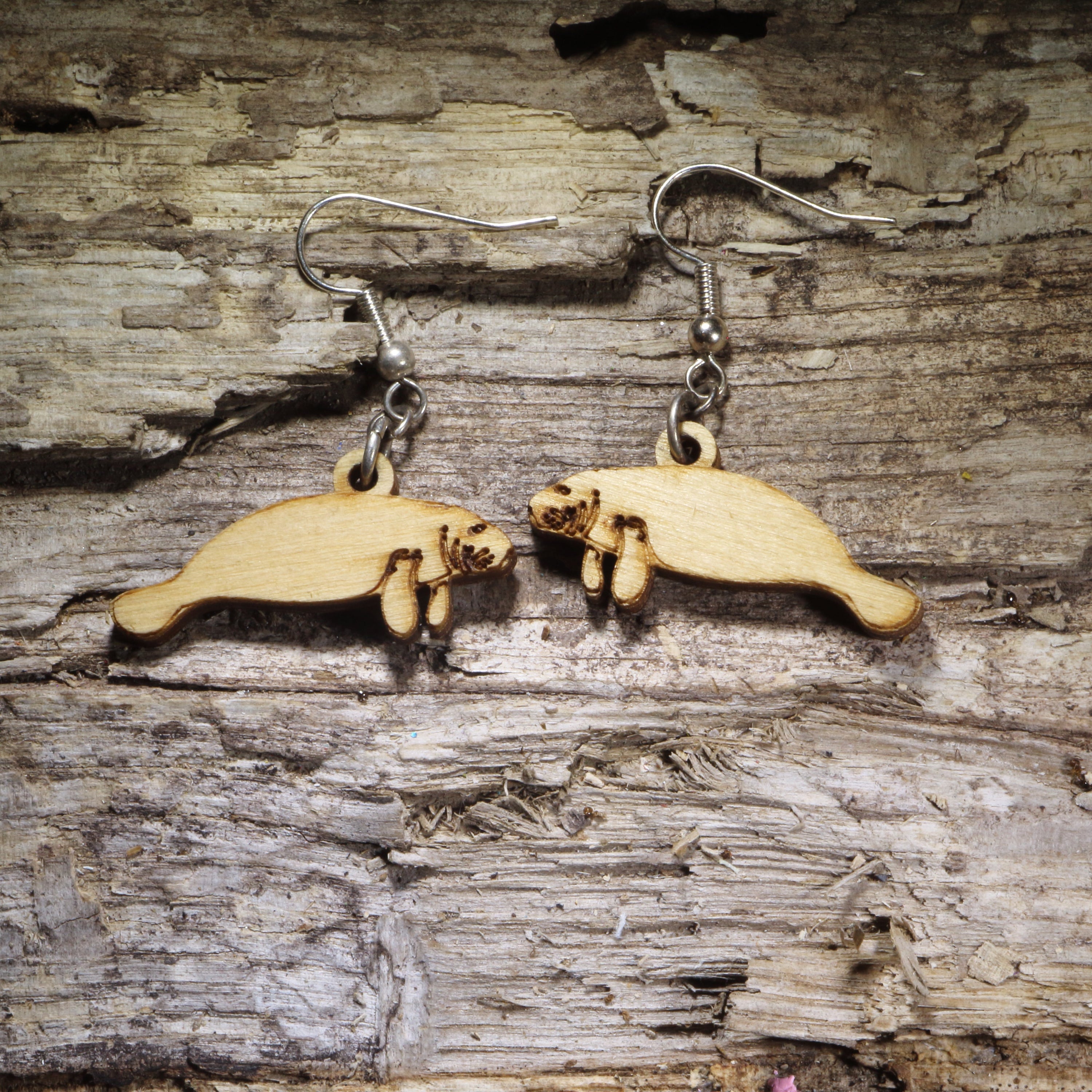 Handcrafted manatee wooden dangle earrings featuring an adorable laser-cut manatee design in natural Baltic birch wood. Lightweight wooden earrings with hypoallergenic .925 sterling silver hooks, perfect for manatee lovers, ocean life enthusiasts, Florida wildlife fans, marine mammal lovers, coastal gifts, and handmade sea life jewelry.