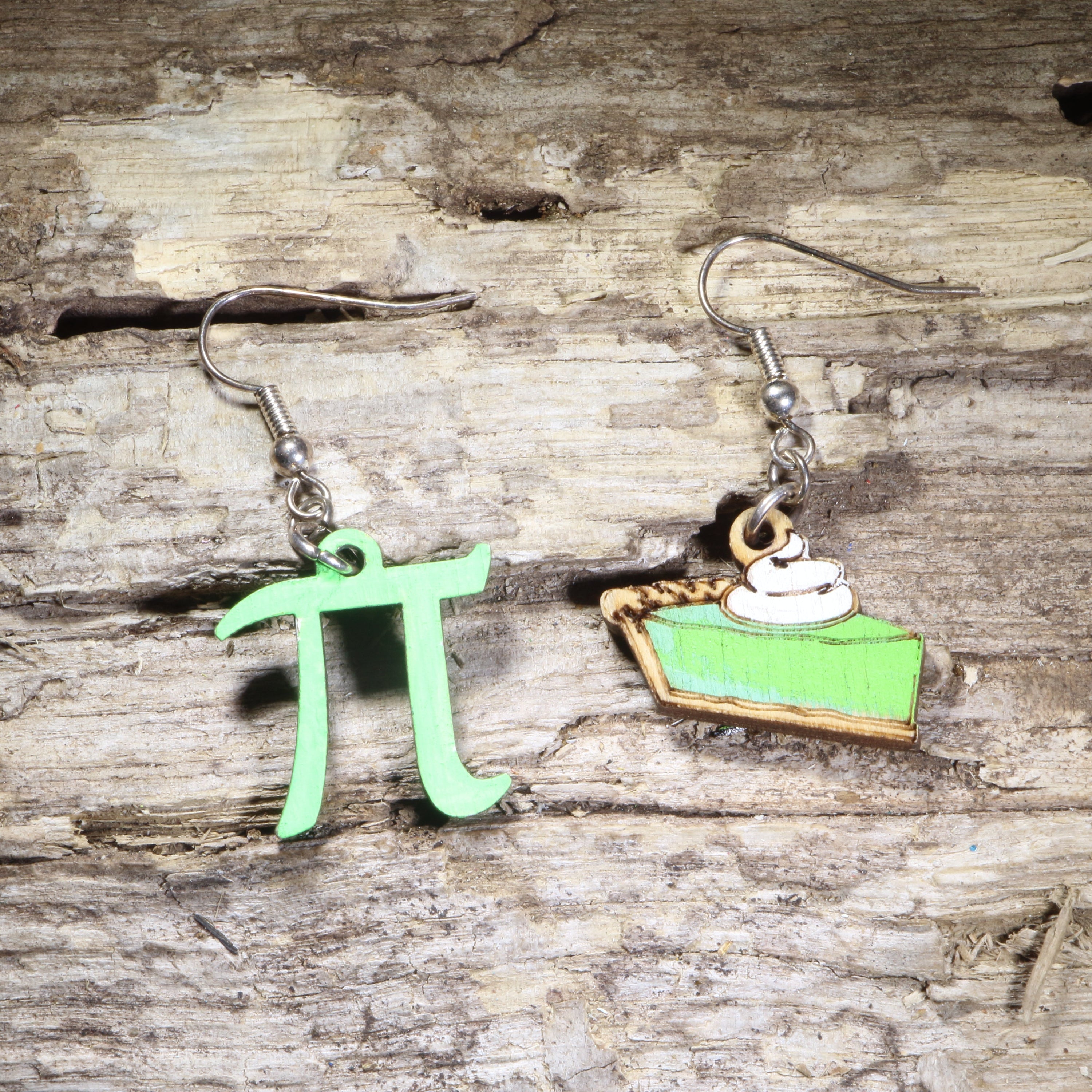 Handcrafted mismatched wooden dangle earrings featuring a bright green pi symbol and a slice of green key lime pie with whipped cream. Lightweight math and dessert earrings with hypoallergenic .925 sterling silver hooks, perfect for math teachers, STEM enthusiasts, pie lovers, and quirky geeky jewelry fans.