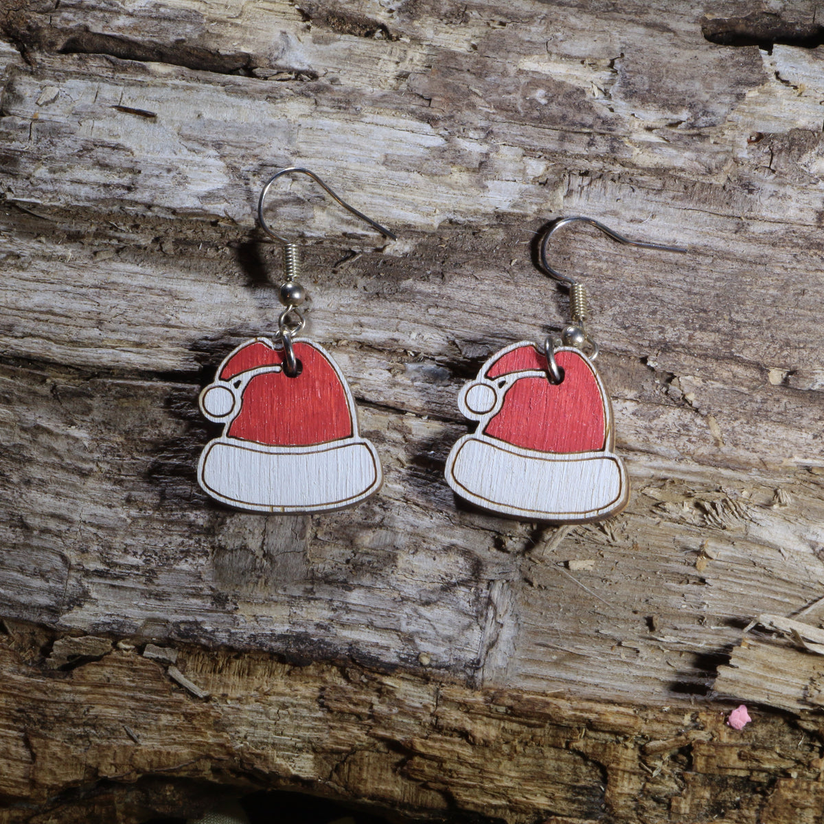 Handcrafted wooden Santa hat dangle earrings featuring the iconic red and white Christmas hat. These lightweight holiday earrings are hand-painted and finished with hypoallergenic .925 sterling silver hooks, making them perfect for Christmas parties, holiday events, festive outfits, Secret Santa gifts, stocking stuffers, and celebrating the holiday season in cheerful style.