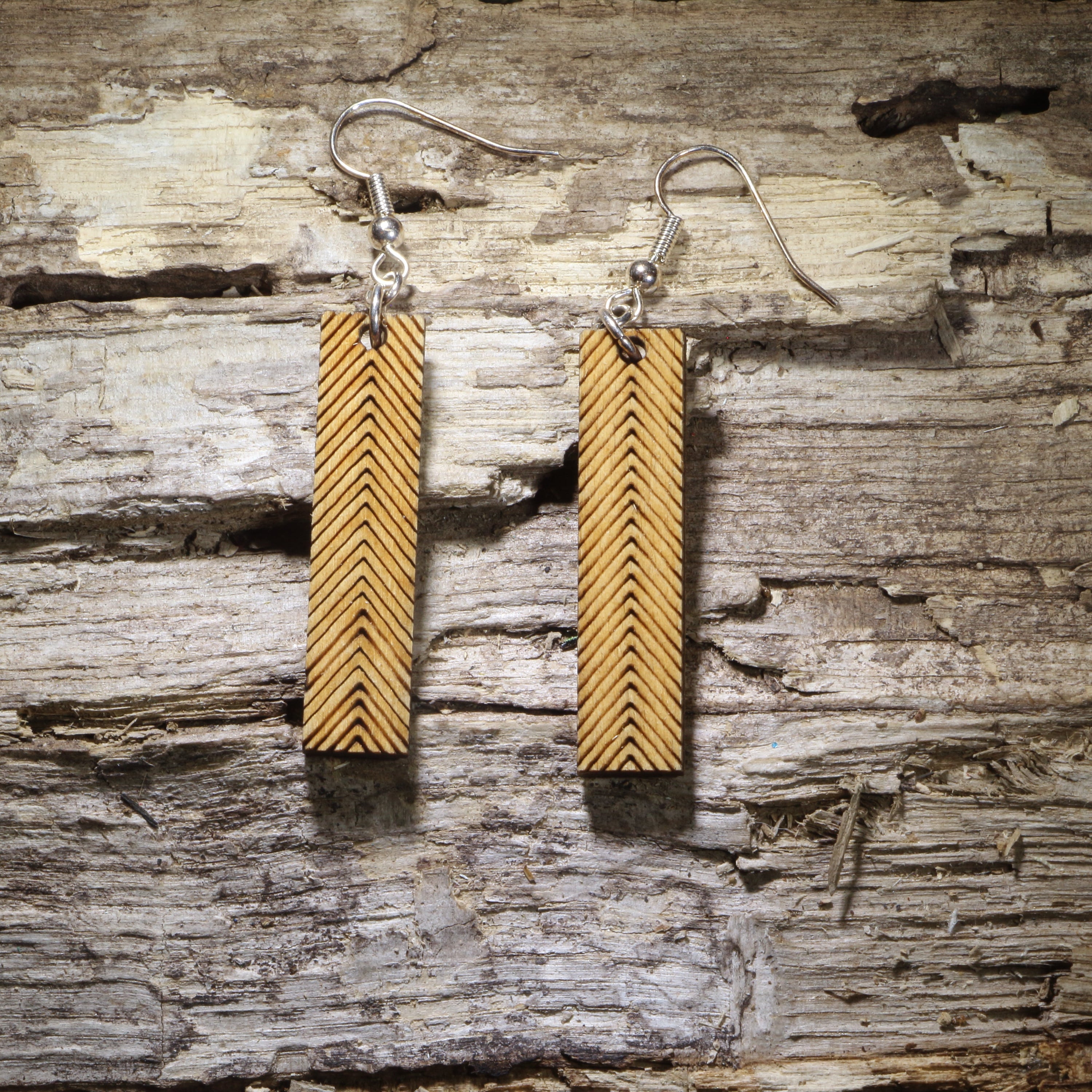 Handcrafted wooden bar dangle earrings featuring an engraved chevron pattern on natural wood. Lightweight geometric earrings with hypoallergenic .925 sterling silver hooks, perfect for minimalist jewelry lovers, boho fashion, modern style, everyday wear, and handmade statement accessories.