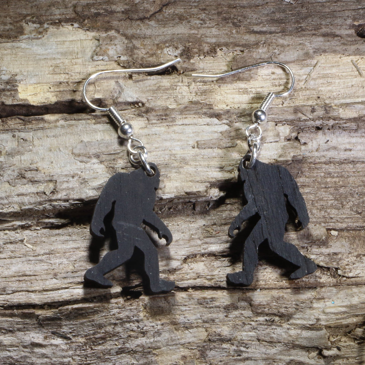 Handmade Bigfoot wooden dangle earrings crafted from lightweight black stained laser-cut wood with hypoallergenic .925 sterling silver hooks. Sasquatch silhouette jewelry perfect for cryptid fans, Bigfoot believers, hikers, campers, and outdoor adventure lovers.