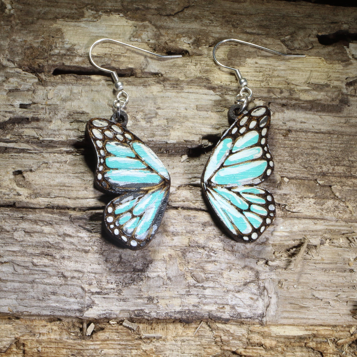 Handmade blue butterfly wing wooden dangle earrings featuring vibrant blue butterfly wings with detailed engraved accents. Lightweight nature-inspired earrings crafted from wood with hypoallergenic .925 sterling silver hooks, perfect for butterfly lovers, gardeners, nature enthusiasts, insect fans, and unique woodland jewelry collectors.
