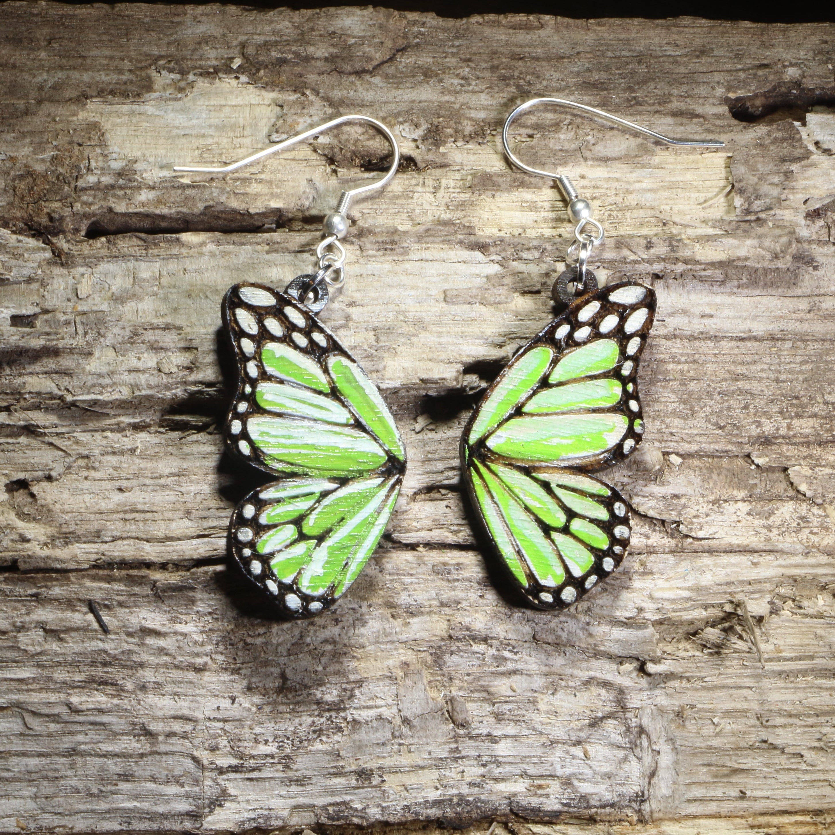 Handmade green butterfly wing wooden dangle earrings featuring vibrant green butterfly wings with detailed engraved accents. Lightweight nature-inspired earrings crafted from wood with hypoallergenic .925 sterling silver hooks, perfect for butterfly lovers, gardeners, nature enthusiasts, insect fans, and unique woodland jewelry collectors.