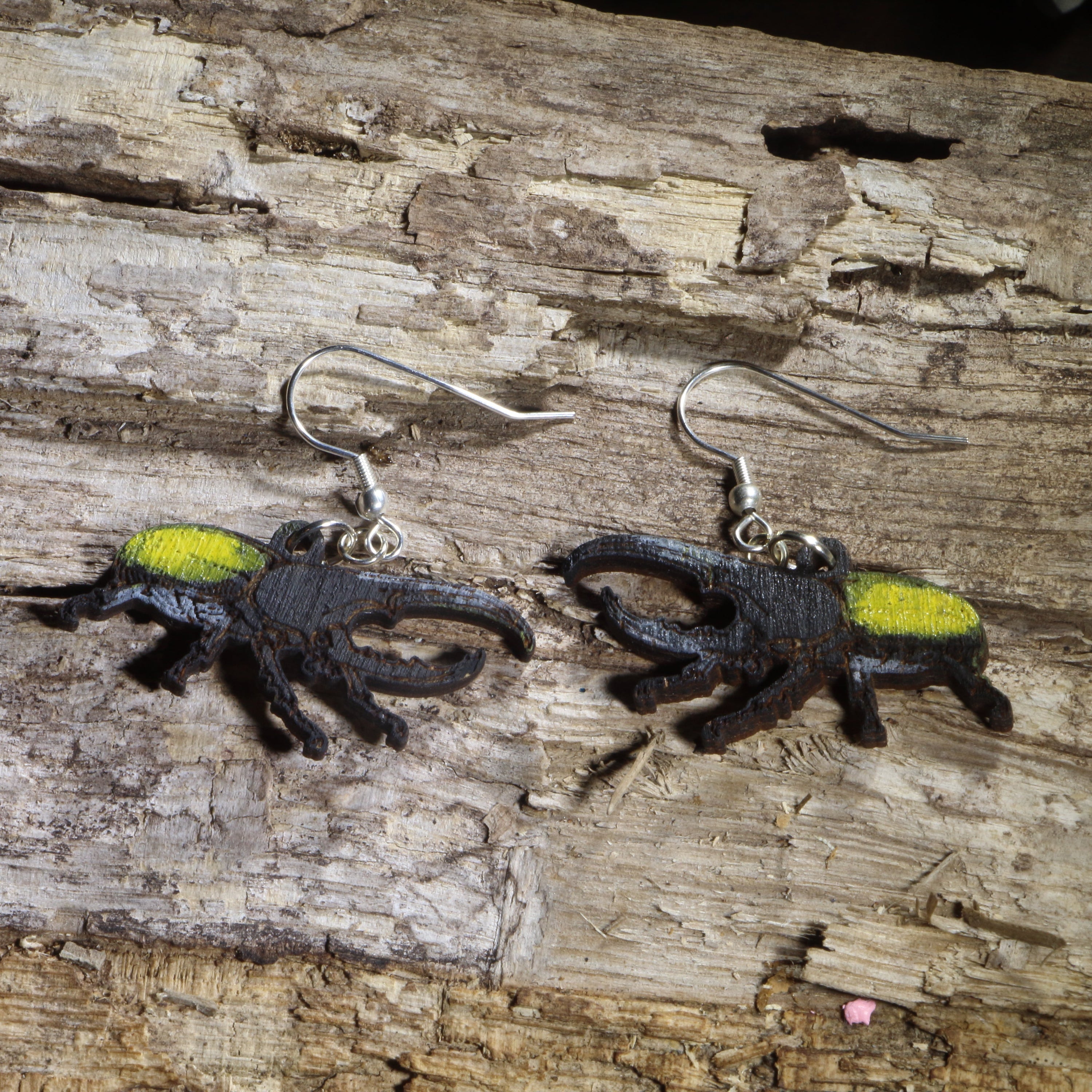 Hand-painted wooden Hercules beetle dangle earrings with black bodies and bright yellow wing covers on hypoallergenic .925 sterling silver hooks. Lightweight insect jewelry for beetle collectors and nature lovers.