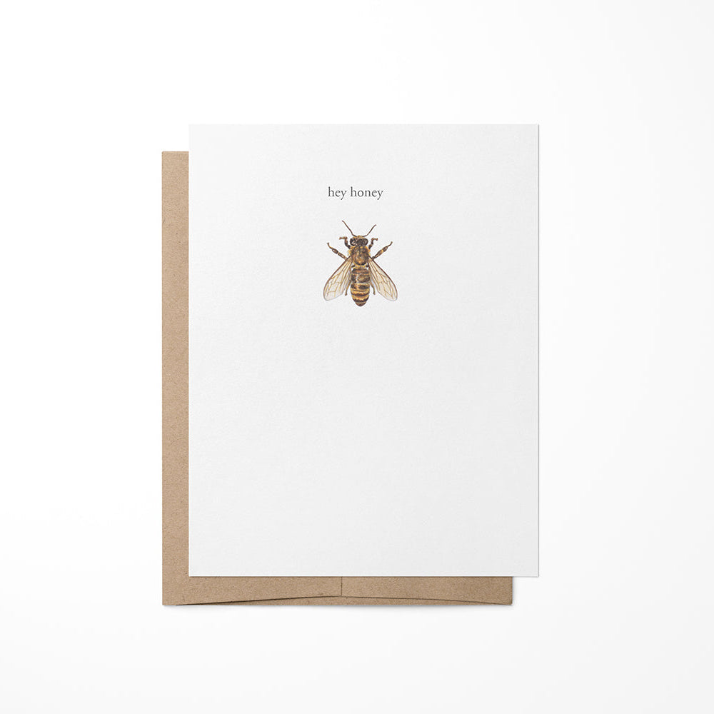 A greeting card with a kraft envelope featuring a watercolor painting of a honeybee on the front, placed against a white background.
