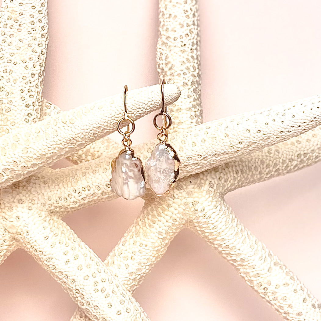 ocean springs organic shape oval drop pearl earrings on pink background with sea stars