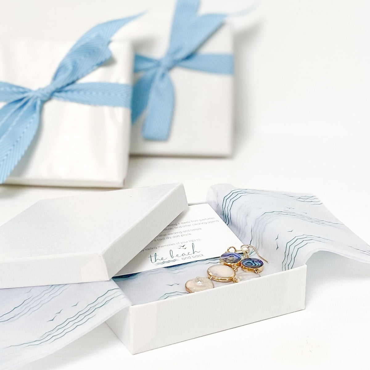 the beach and back gift wrap with signature wave and sea gull pattern tissue paper with white paper wrap and turquoise ribbon bow