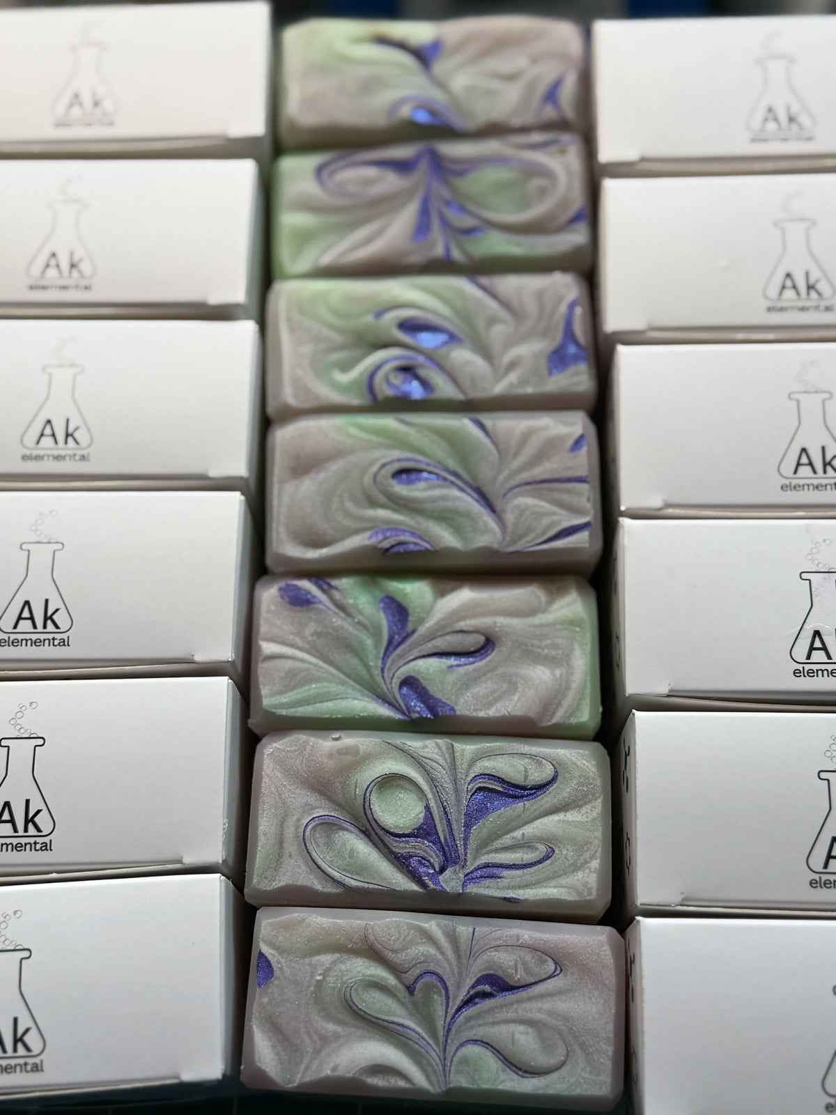Tops of soap boxes and tops of soaps with decorative purple swirls.
