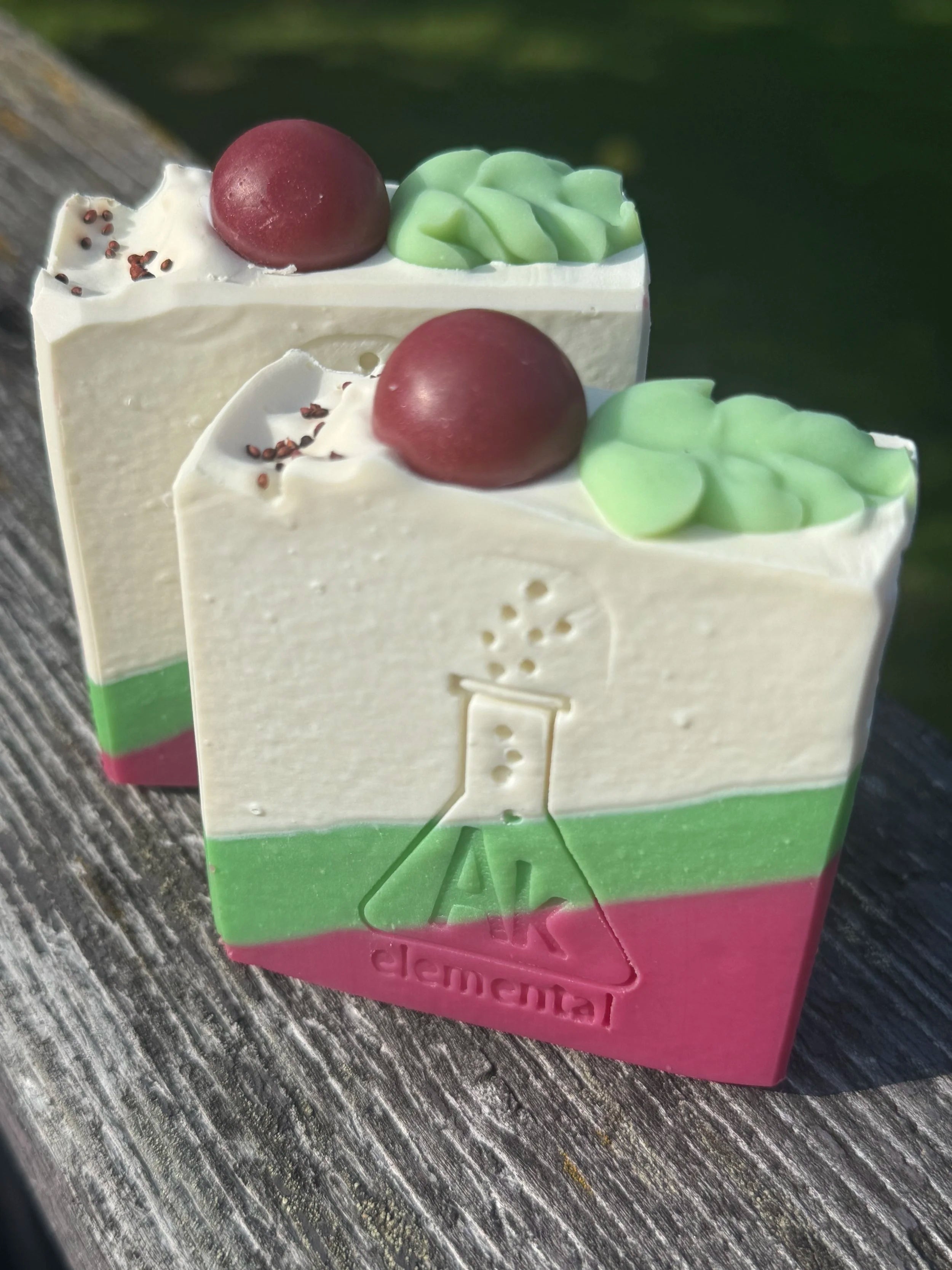 Handcrafted Wild Cranberry soap bar with cream, evergreen green and cranberry red diagonal layers and festive round soap embeds on top.